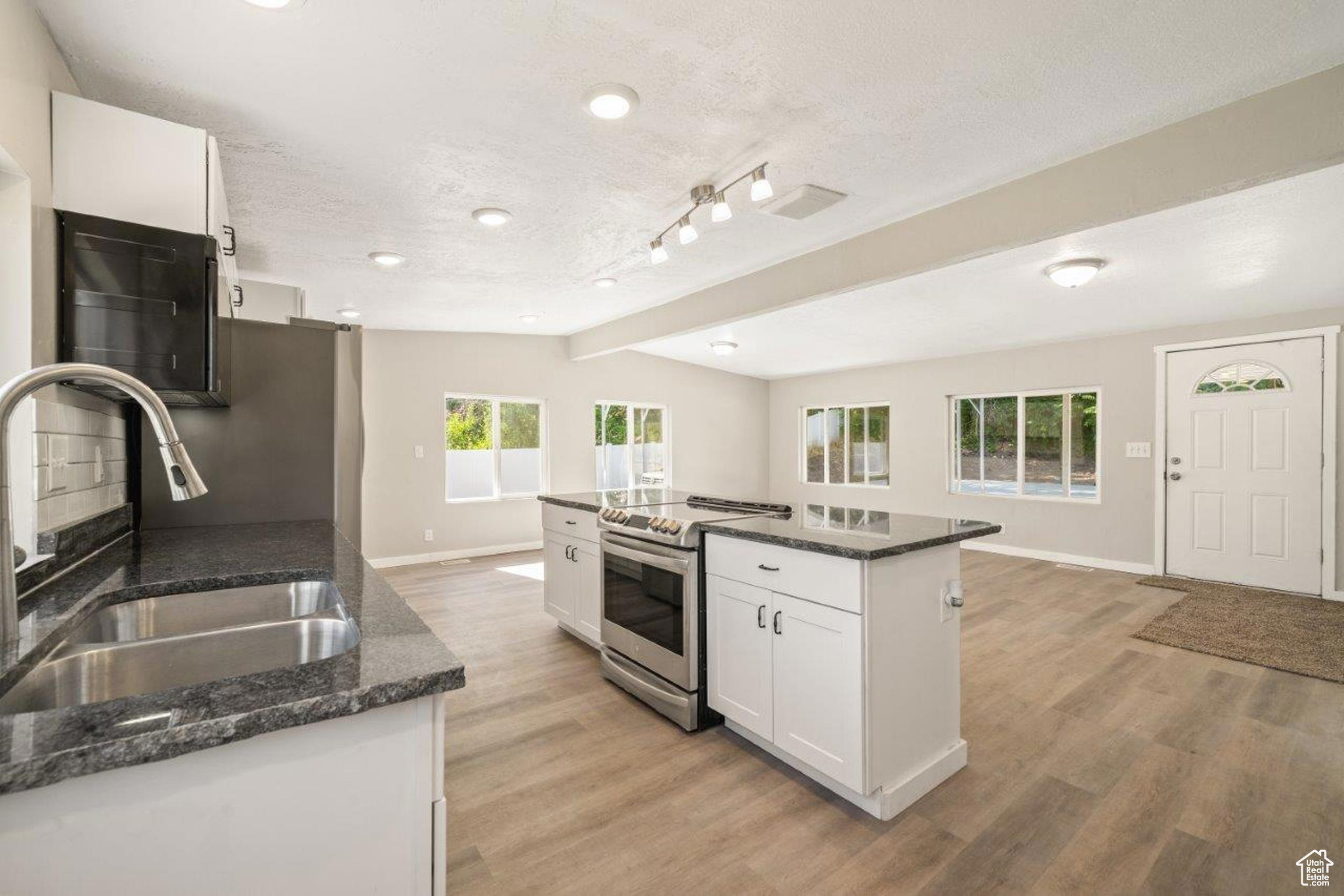 Kitchen featuring sink, light hardwood / wood-style flooring, a kitchen island, stainless steel range, and white cabinets