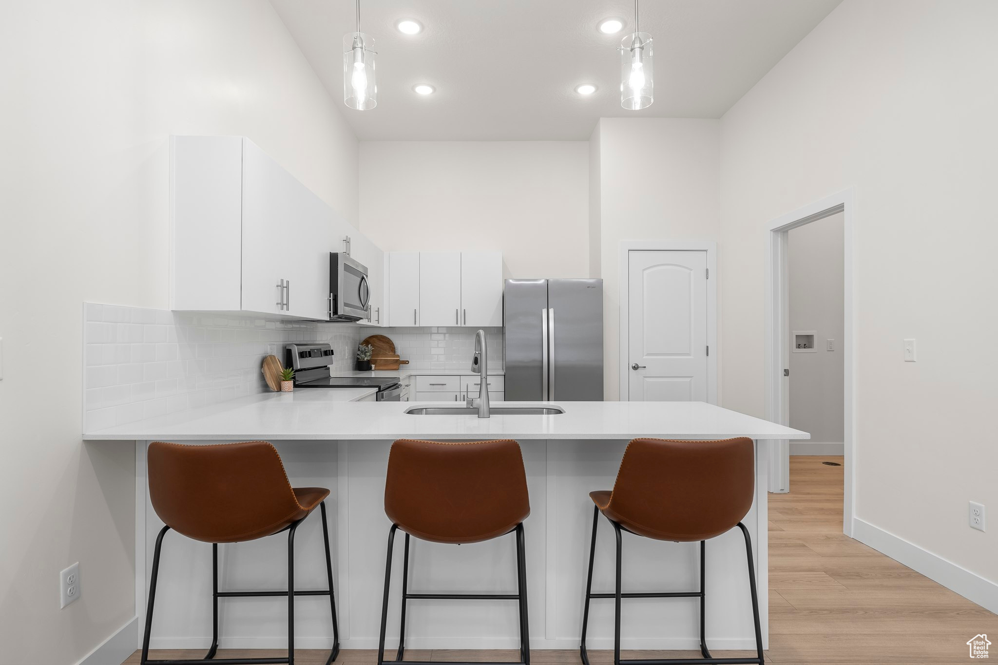 Kitchen featuring sink, kitchen peninsula, stainless steel appliances, and hanging light fixtures