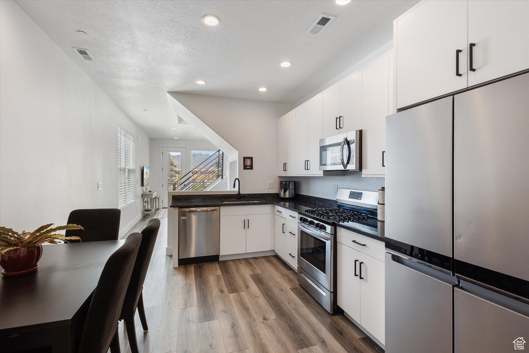 Kitchen featuring sink, light hardwood / wood-style floors, white cabinetry, stainless steel appliances, and kitchen peninsula