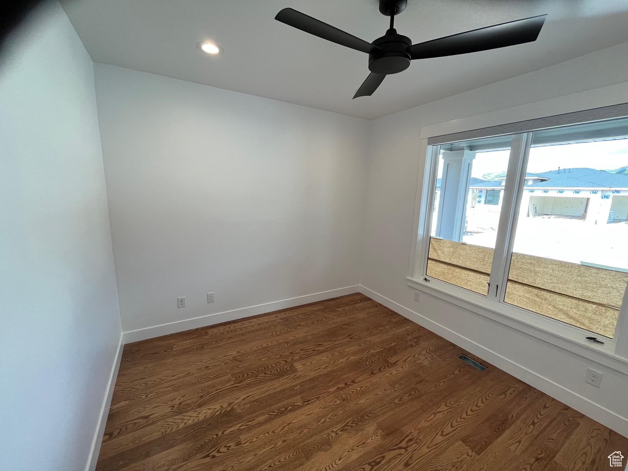 Spare room with ceiling fan and dark wood-type flooring