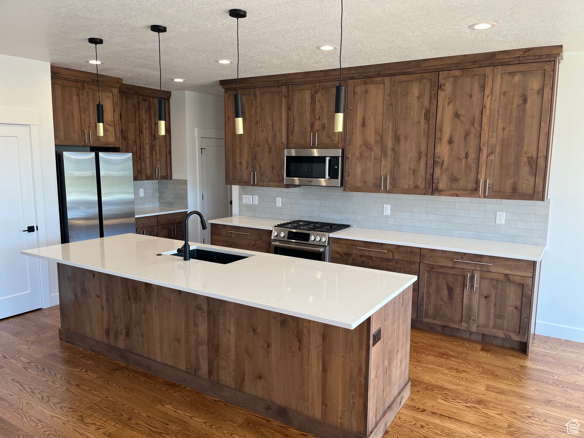 Kitchen with a kitchen island with sink, appliances with stainless steel finishes, sink, and light hardwood / wood-style floors