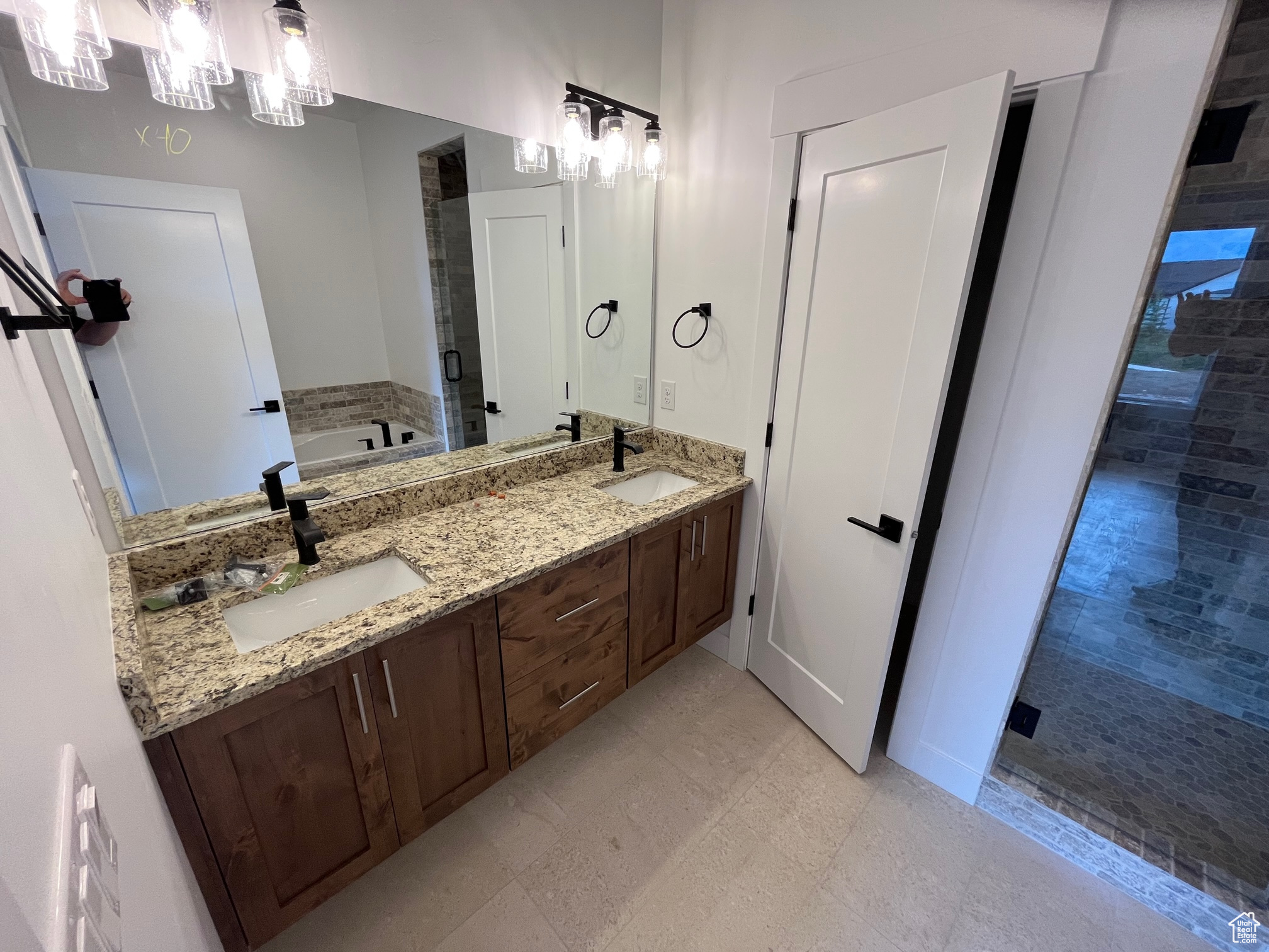 Bathroom with an inviting chandelier, a tub, double vanity, and tile patterned floors