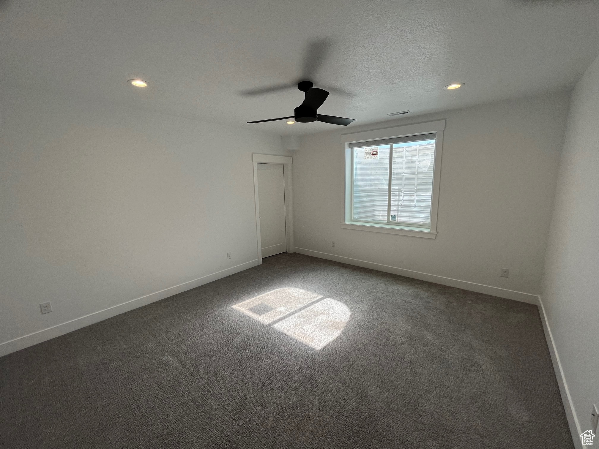 Spare room featuring ceiling fan, carpet, and a textured ceiling