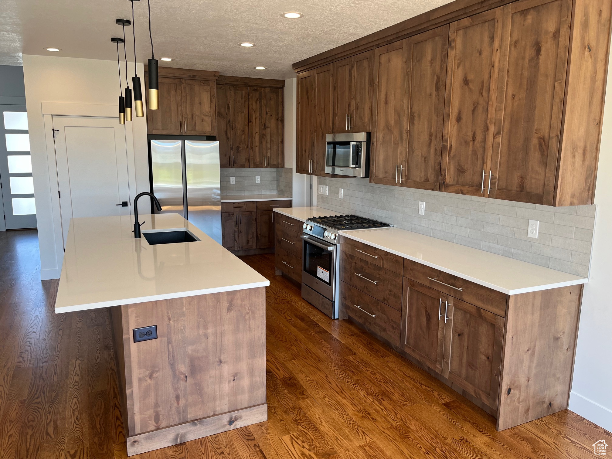 Kitchen with a center island with sink, stainless steel appliances, sink, and dark hardwood / wood-style flooring