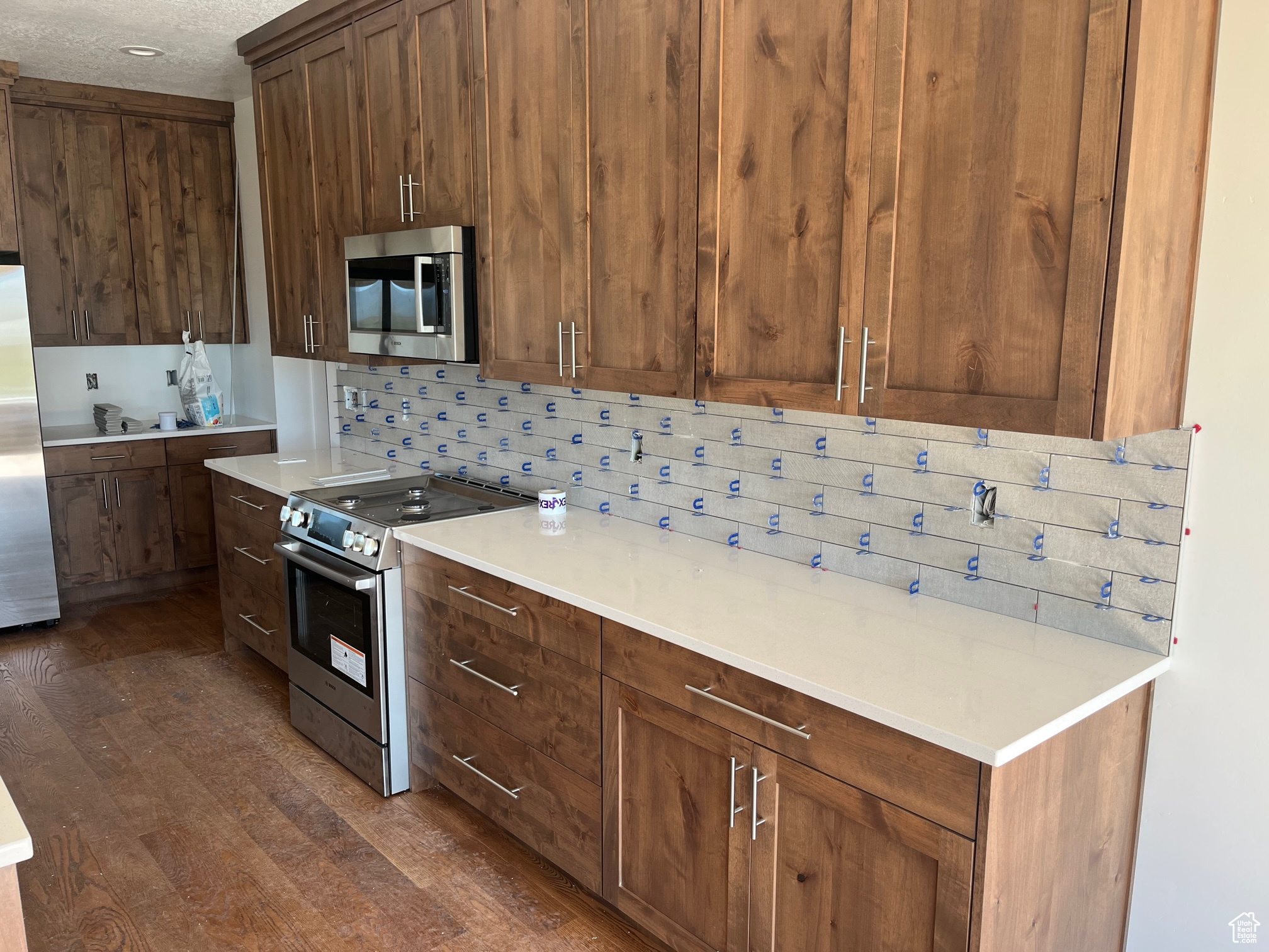 Kitchen with appliances with stainless steel finishes, dark hardwood / wood-style floors, and backsplash