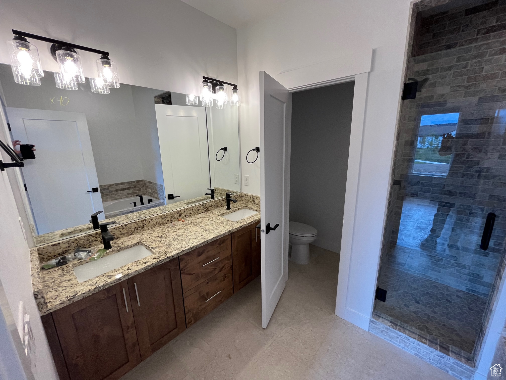 Full bathroom with a chandelier, tile patterned floors, double vanity, independent shower and bath, and toilet