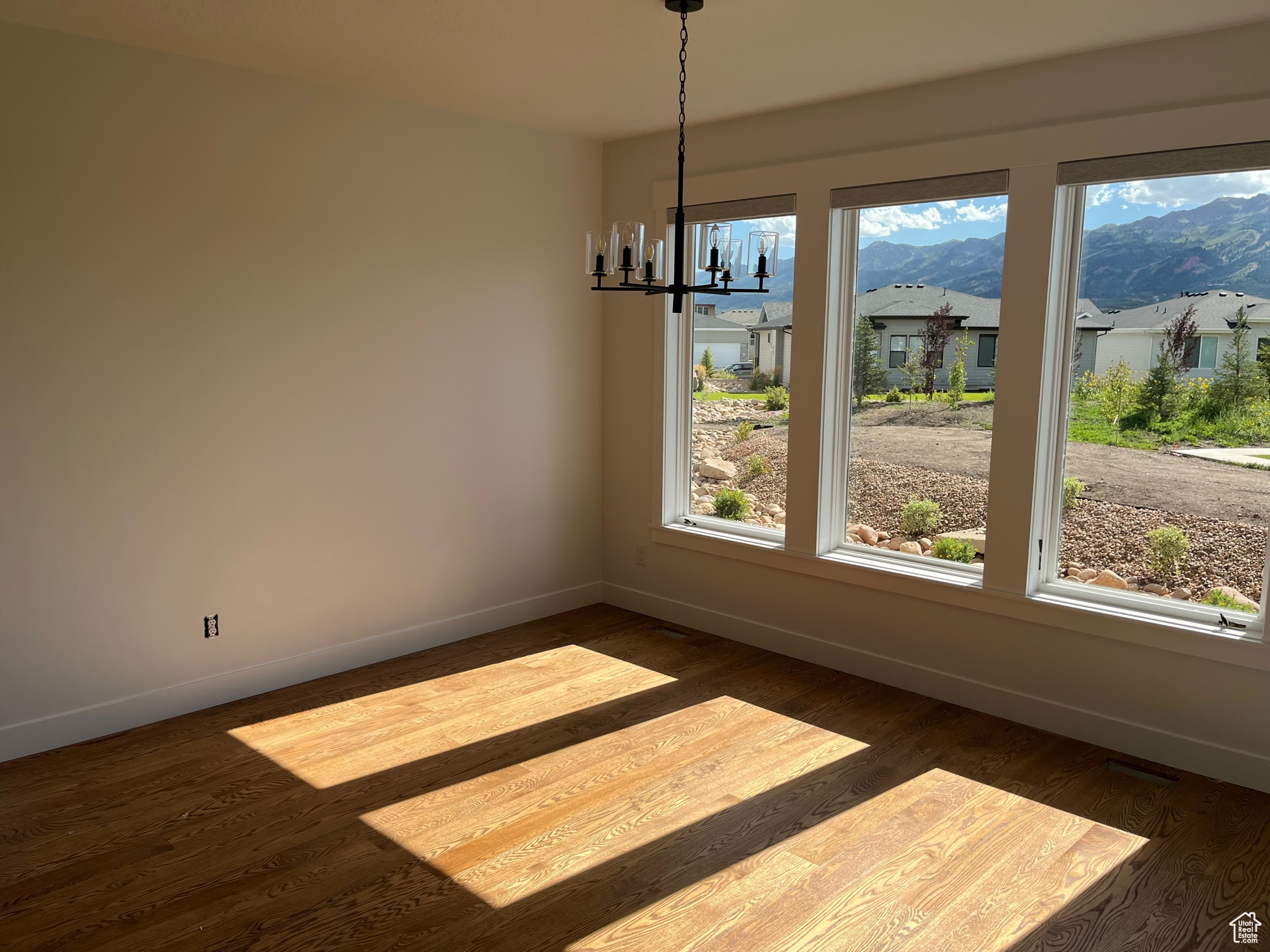 Unfurnished dining area featuring hardwood / wood-style flooring, an inviting chandelier, and a mountain view