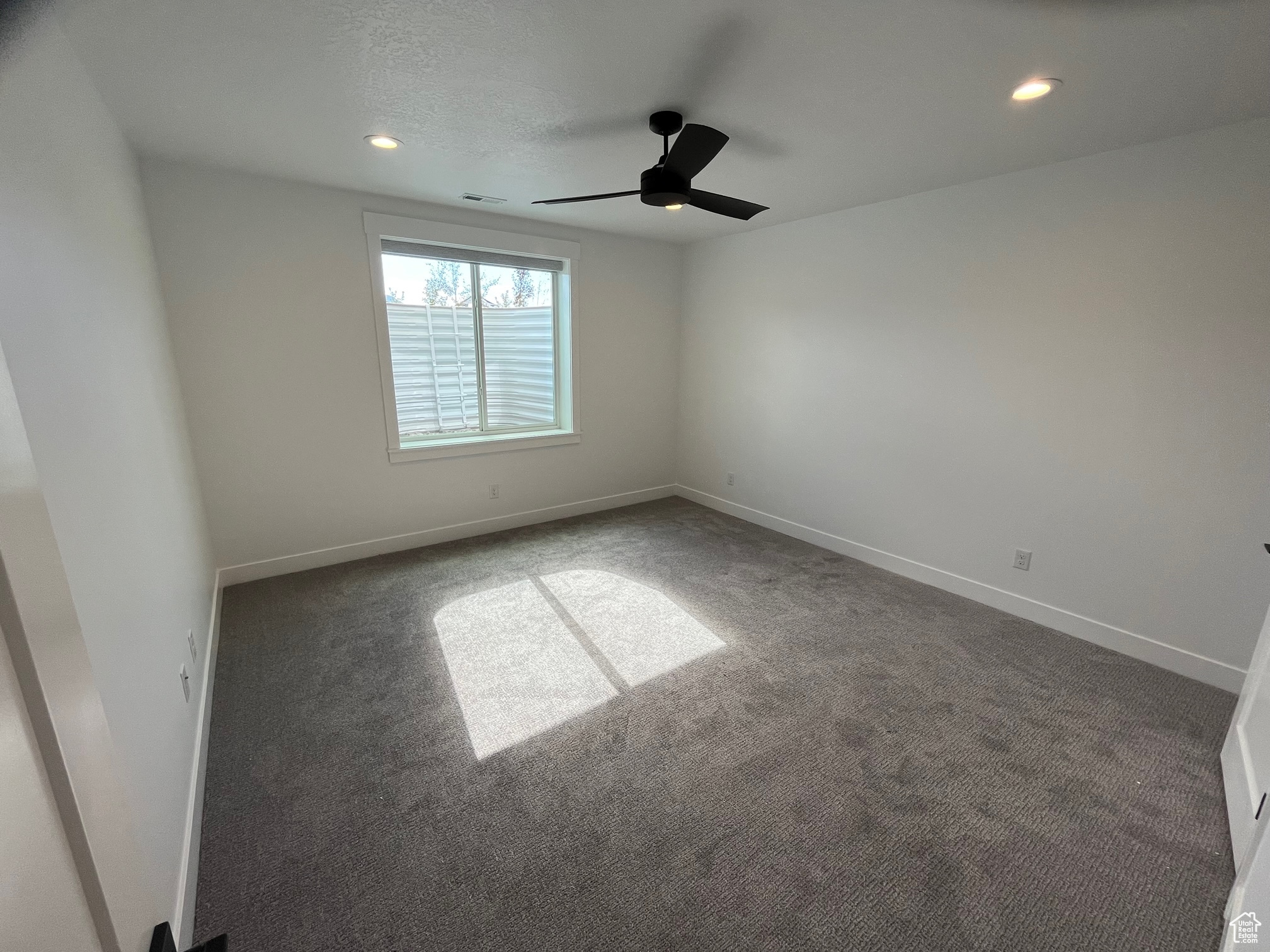 Empty room with ceiling fan and carpet flooring