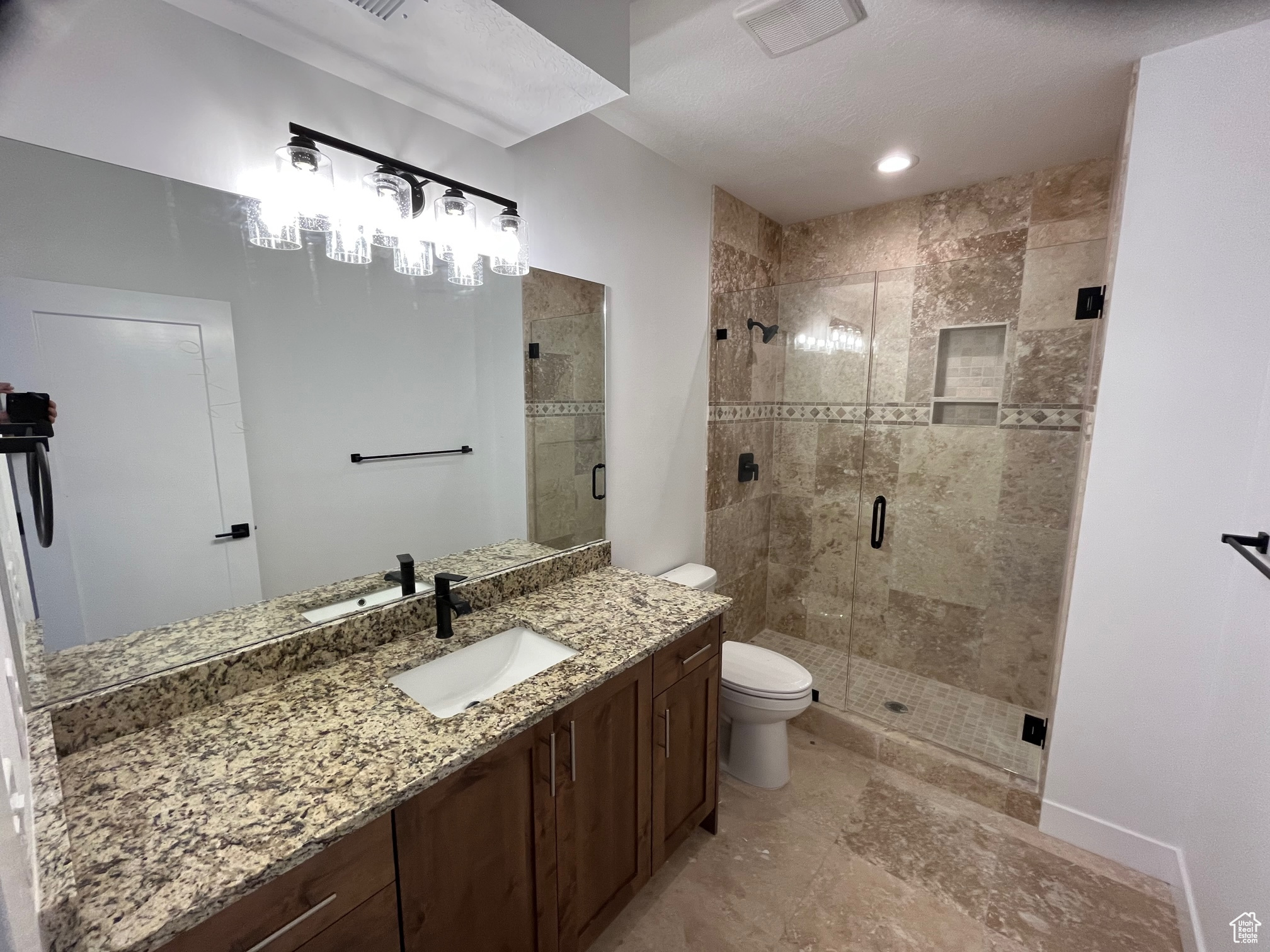 Bathroom featuring tile patterned flooring, a shower with shower door, vanity, and toilet