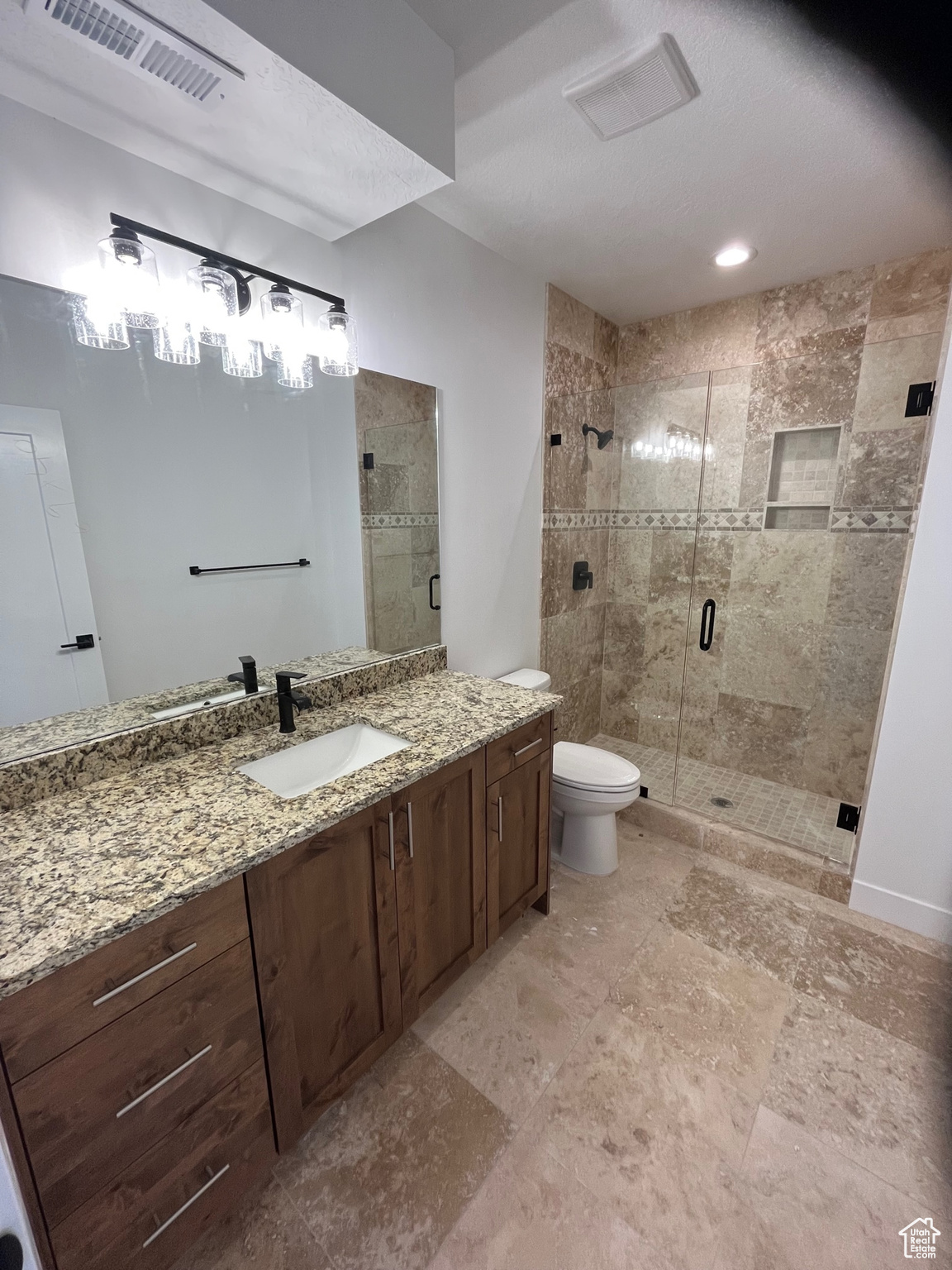 Bathroom with tile patterned flooring, a shower with shower door, vanity, and toilet