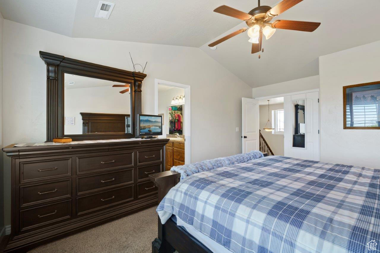 Carpeted bedroom featuring ceiling fan, a closet, a spacious closet, and lofted ceiling