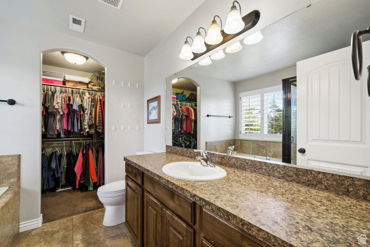 Bathroom with tile patterned flooring, toilet, a bathtub, and vanity