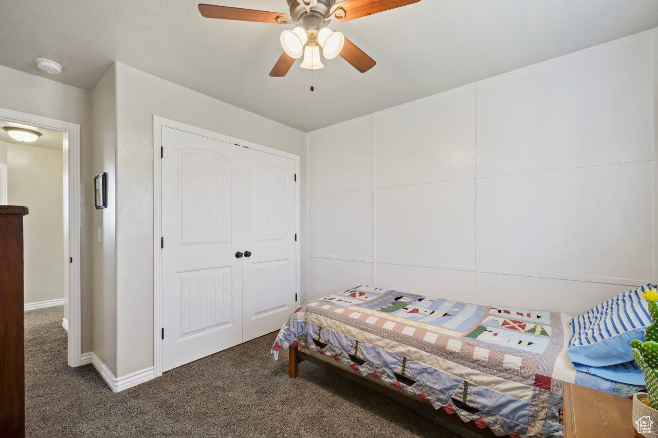 Carpeted bedroom featuring ceiling fan and a closet