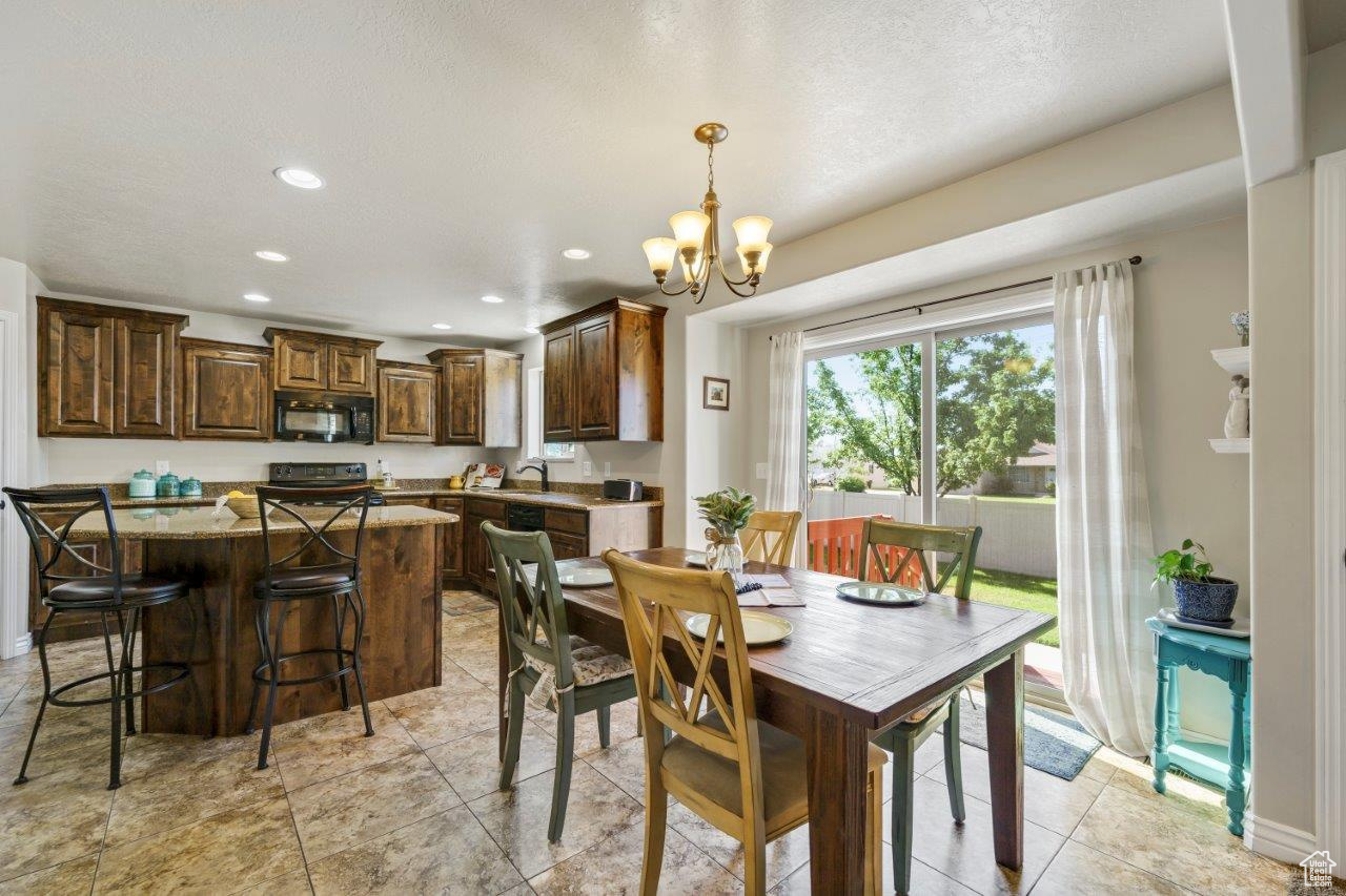 Tiled dining area with sink, a textured ceiling, and an inviting chandelier