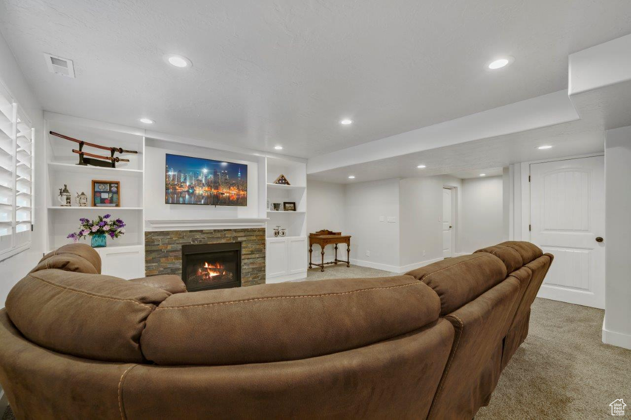 Living room with carpet floors, built in features, and a fireplace