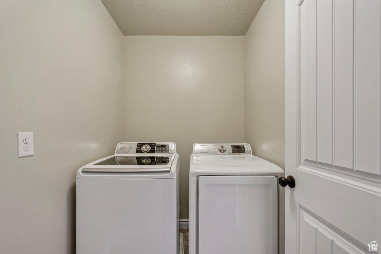 Washroom featuring a textured ceiling and washer and dryer