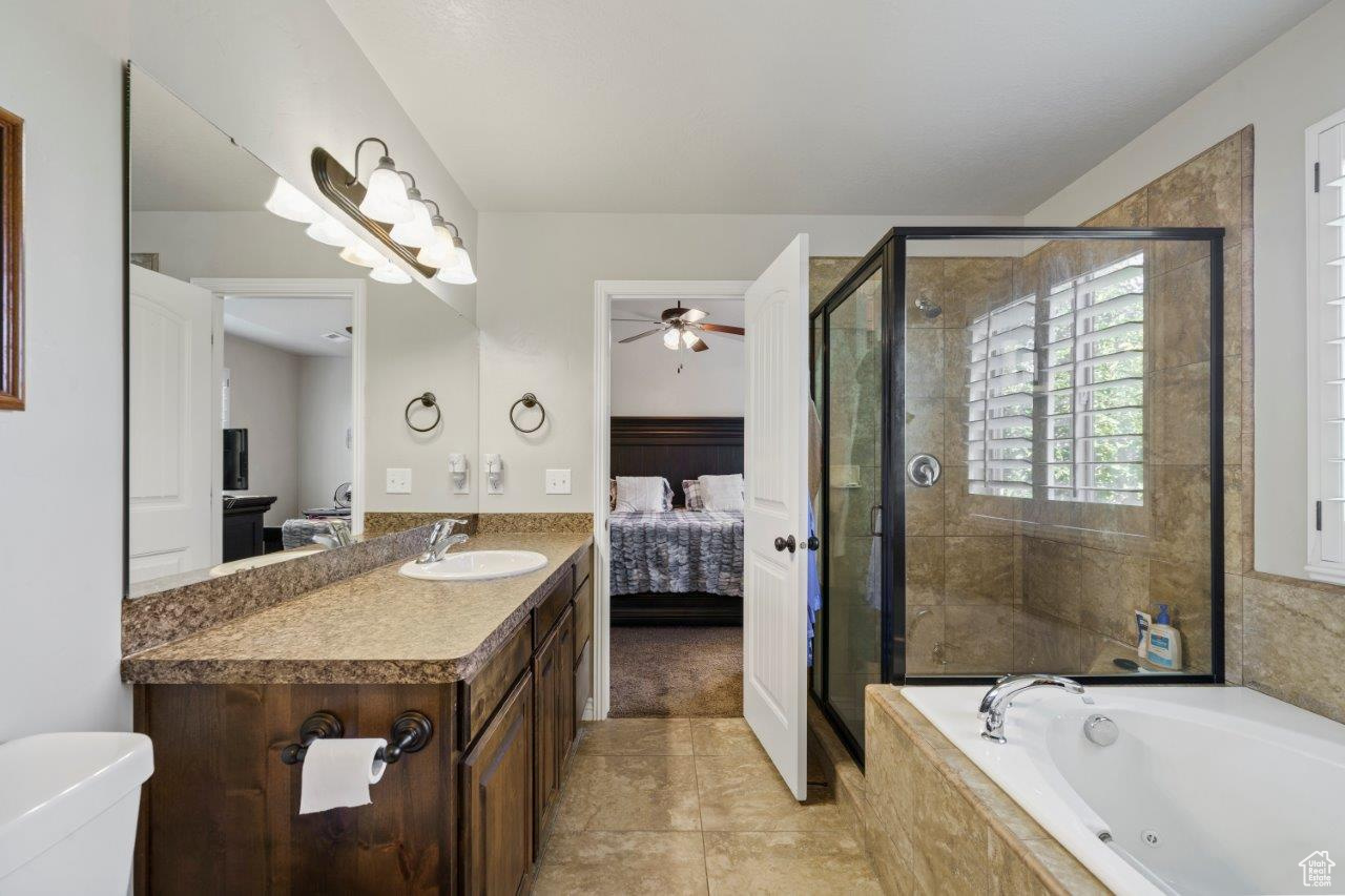 Full bathroom featuring ceiling fan, toilet, vanity, tile patterned floors, and shower with separate bathtub