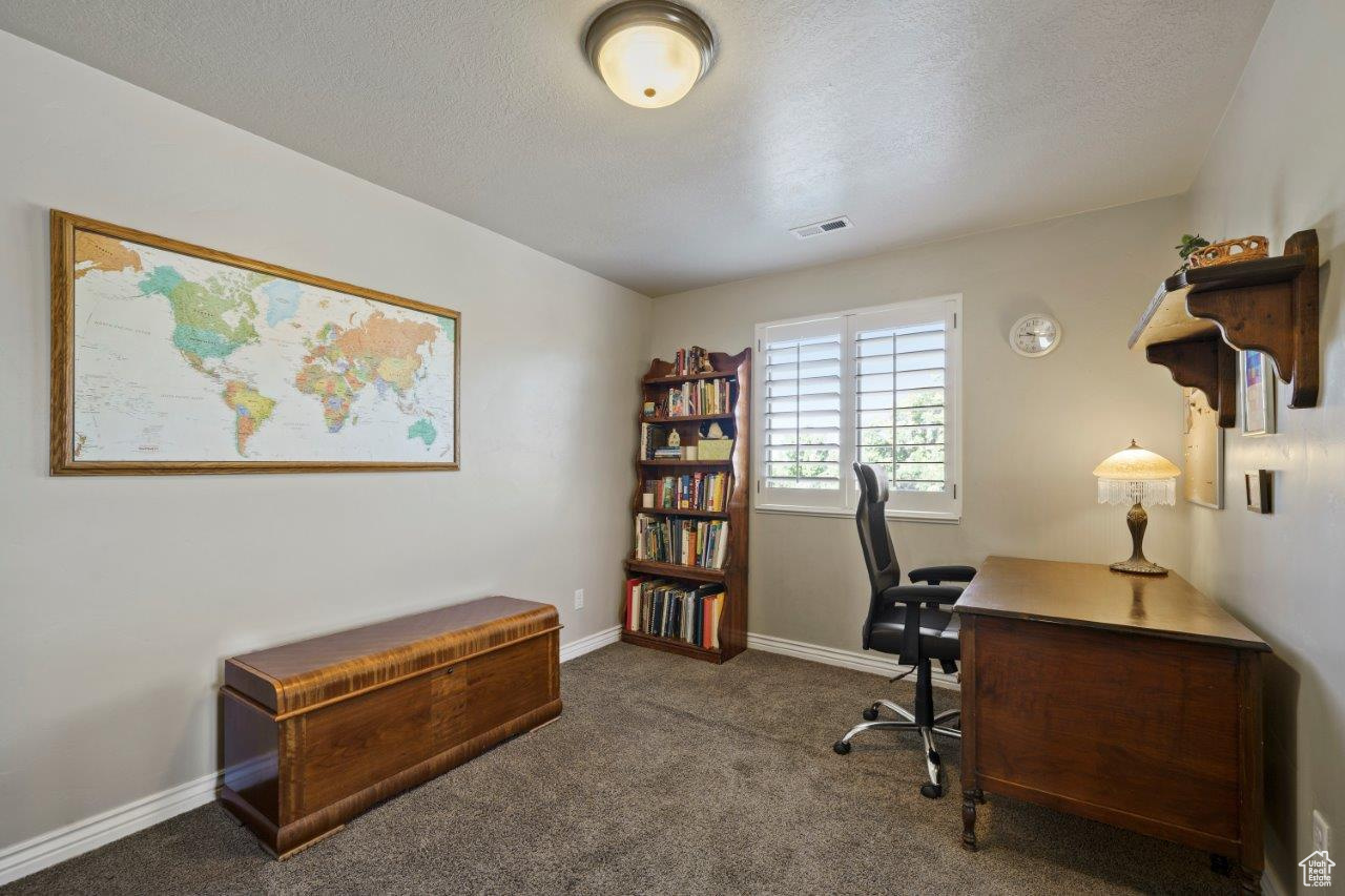 Upstairs Loft/ Home office featuring dark colored carpet and a textured ceiling