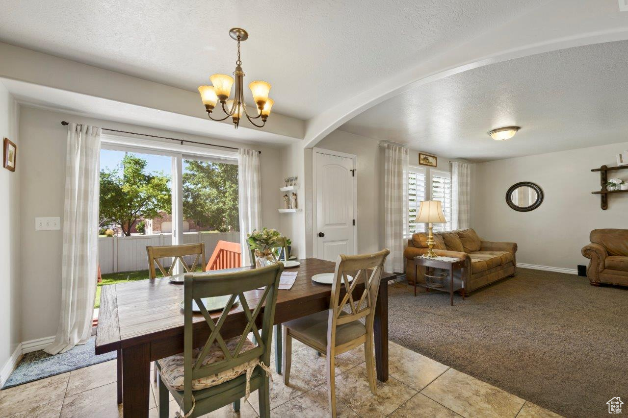 Tiled dining area featuring a notable chandelier and a textured ceiling