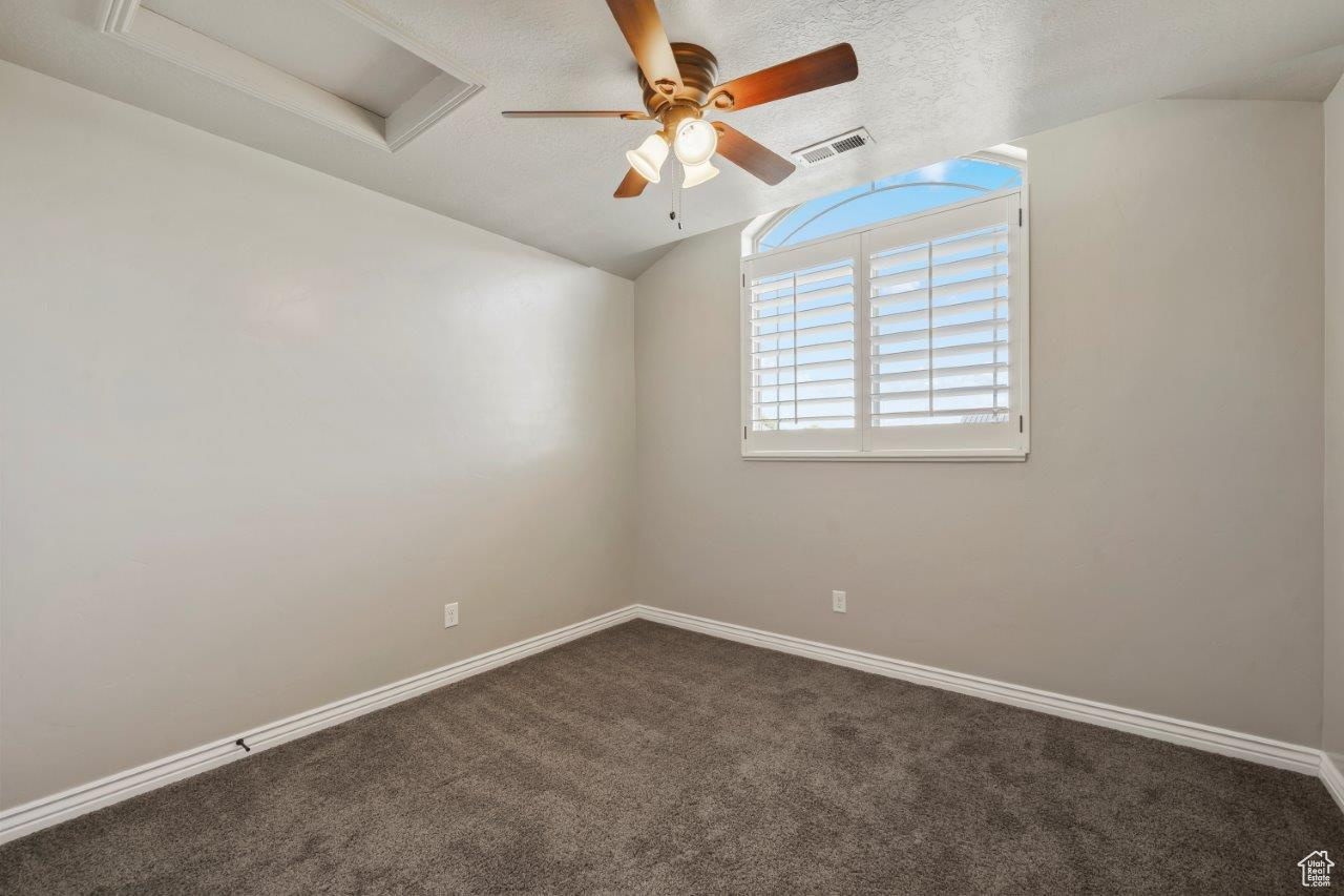 Carpeted spare room featuring ceiling fan and a textured ceiling