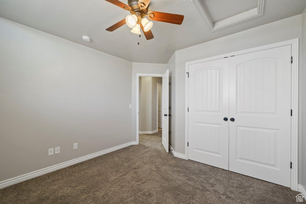 Unfurnished bedroom featuring ceiling fan, a closet, and carpet floors