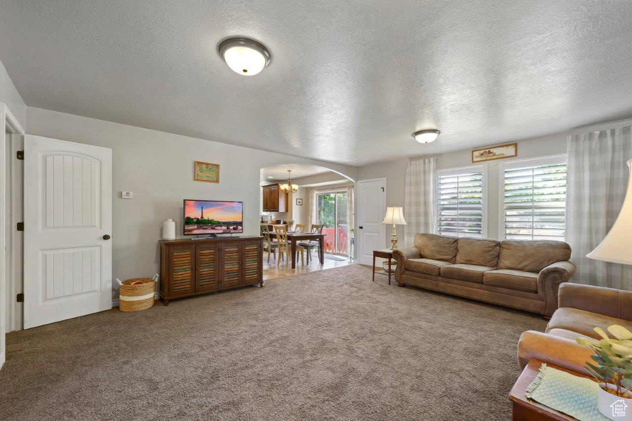 Carpeted living room featuring a textured ceiling and an inviting chandelier