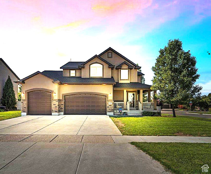 View of front of home with a garage, a porch, and a yard