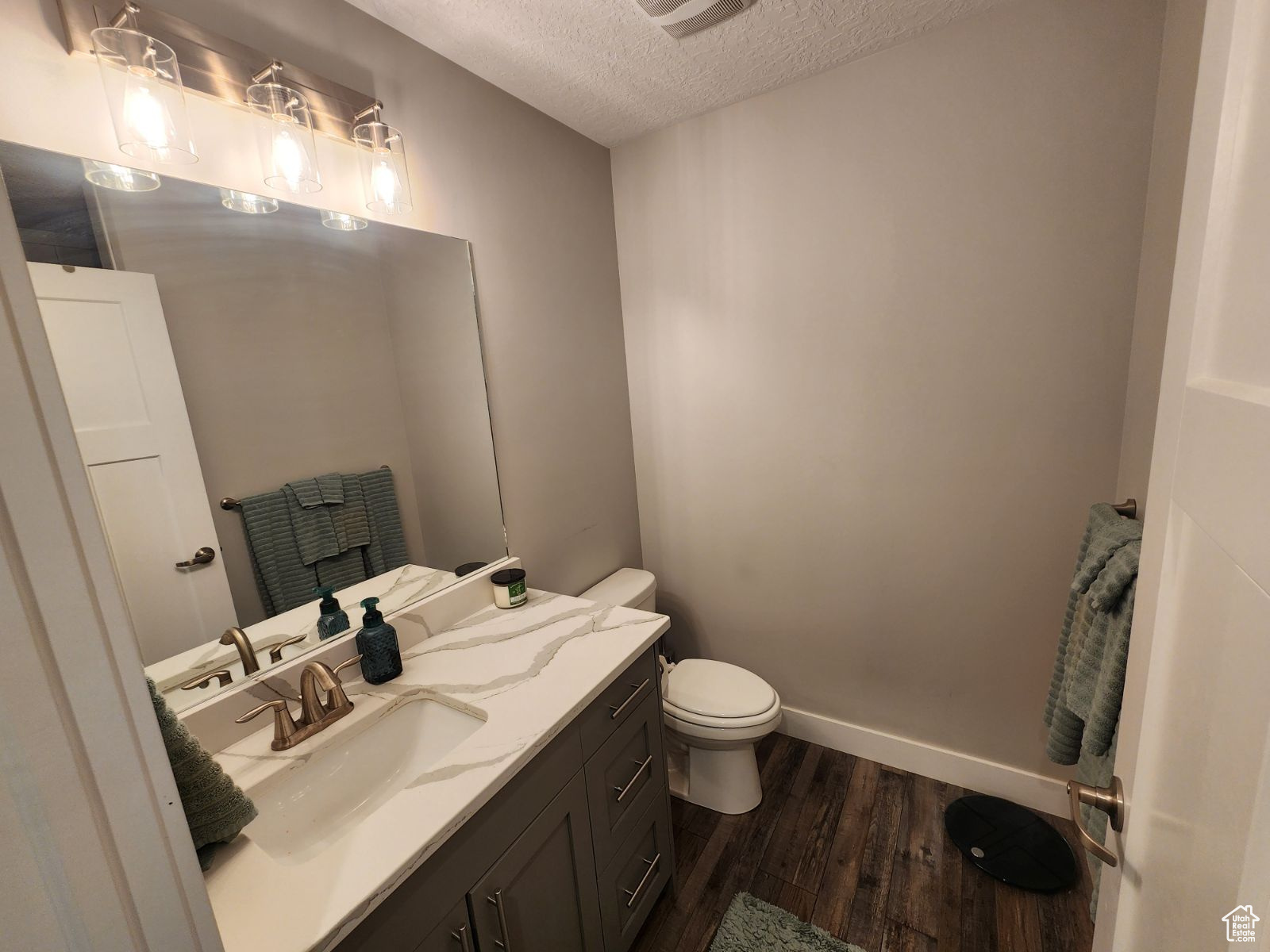 Bathroom featuring a textured ceiling, toilet, hardwood / wood-style floors, and vanity