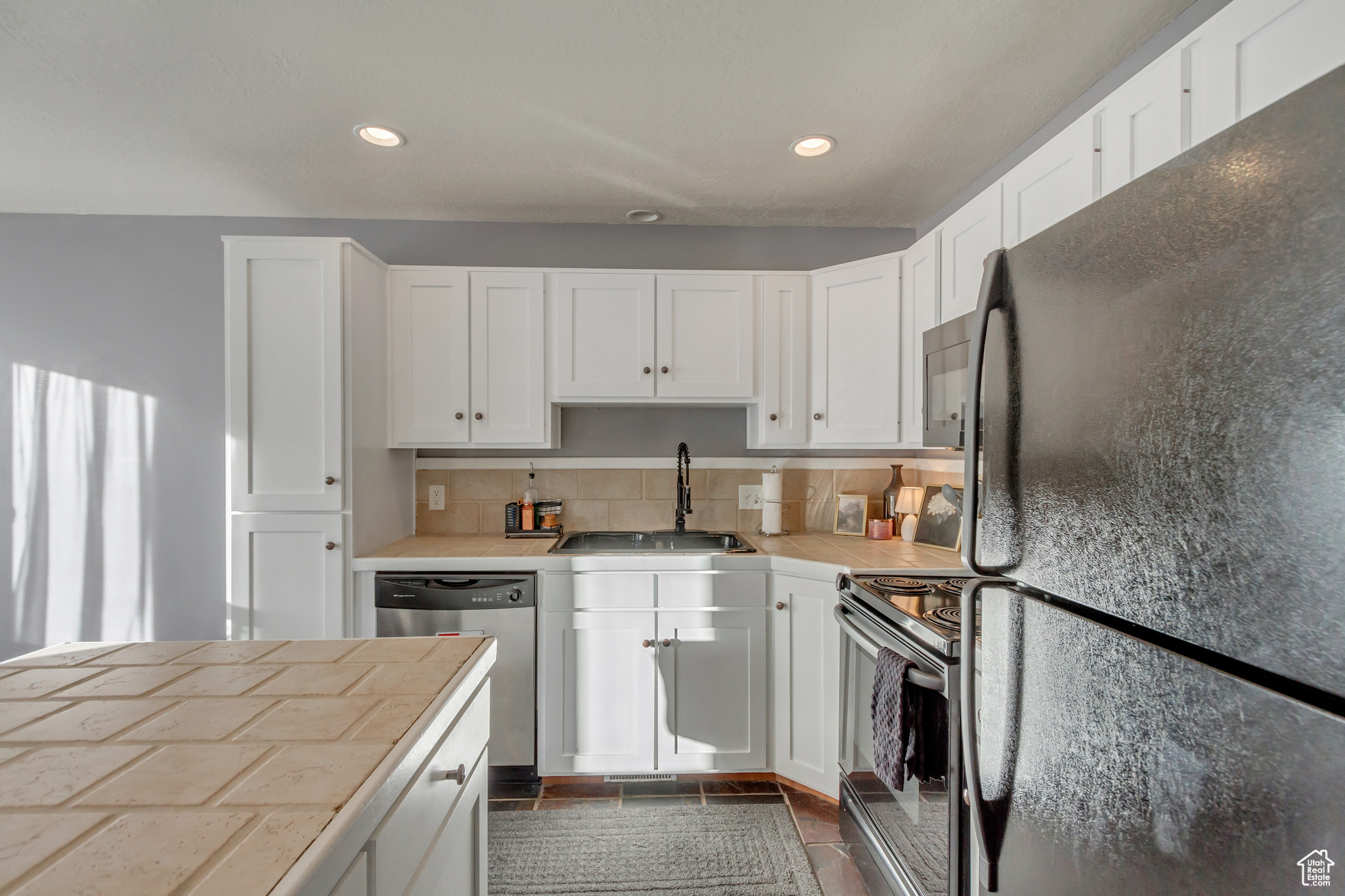 Kitchen with sink, tasteful backsplash, white cabinetry, and appliances with stainless steel finishes