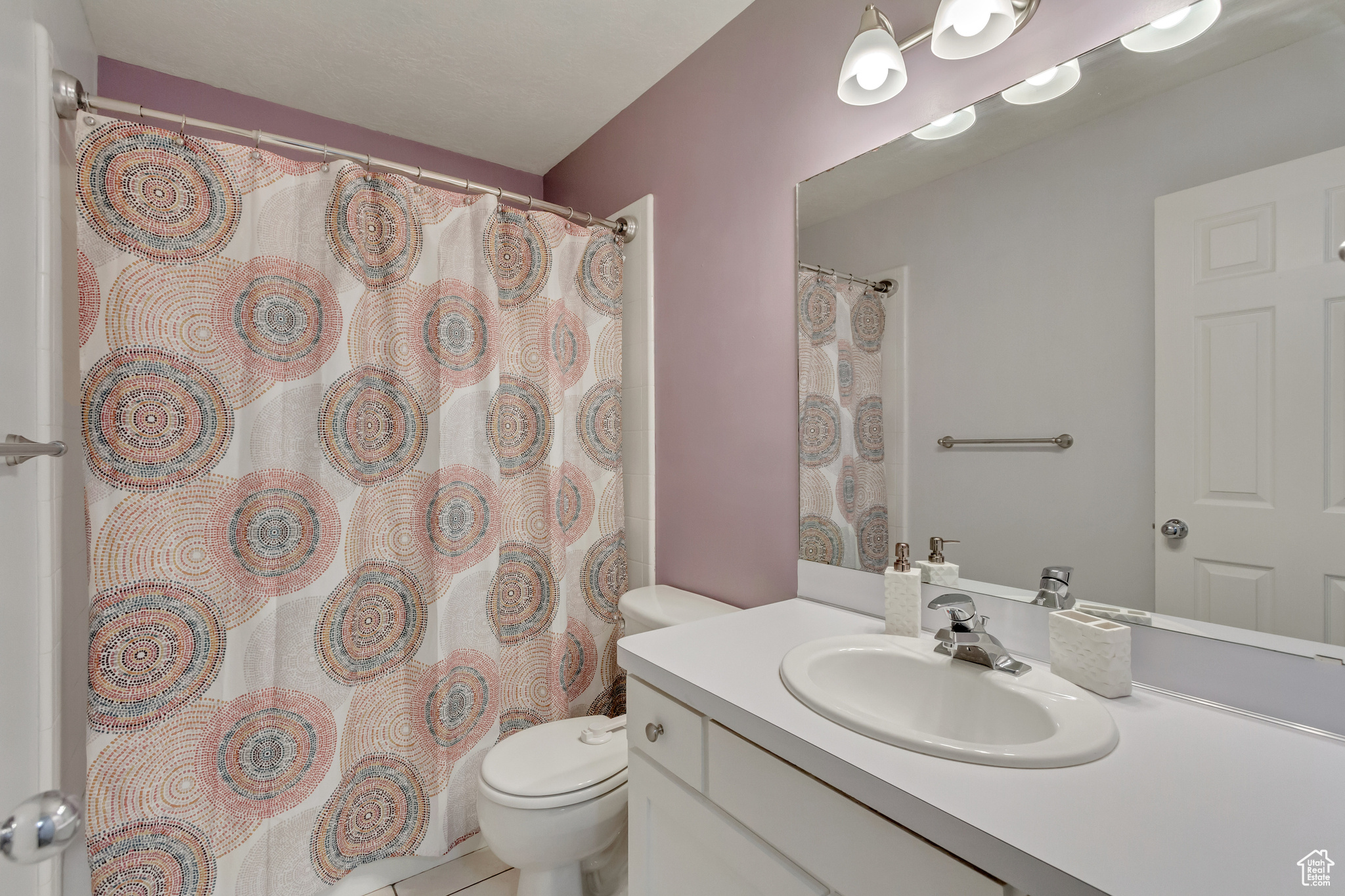 Bathroom featuring tile patterned flooring, toilet, vanity, and a shower with curtain