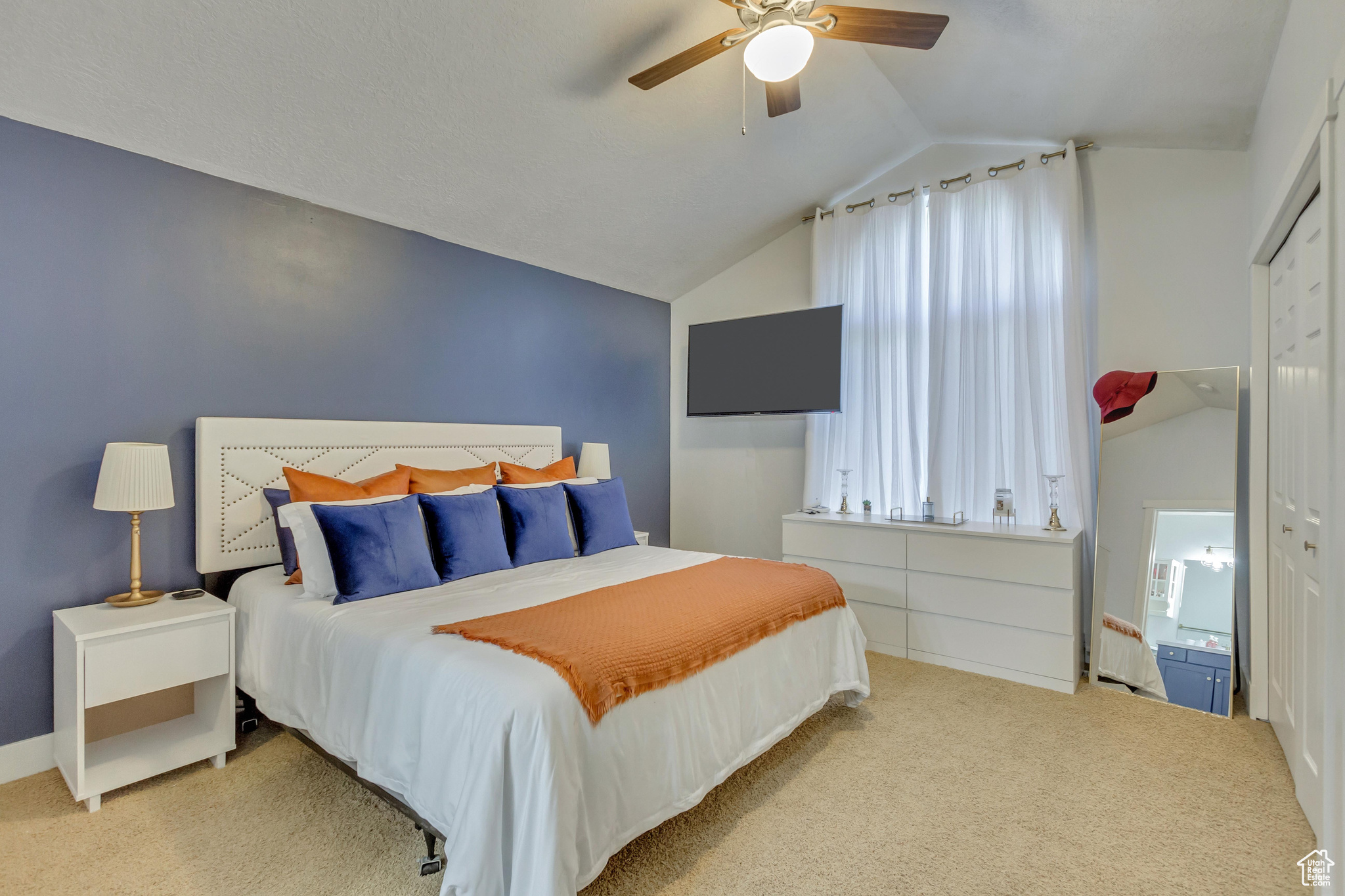 Carpeted bedroom with ceiling fan, a closet, and vaulted ceiling