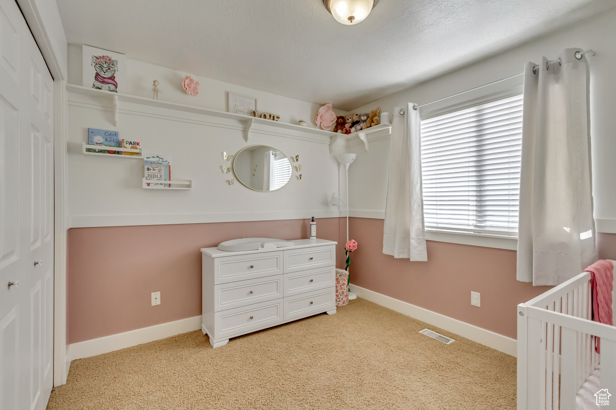 Carpeted bedroom with a crib and a closet