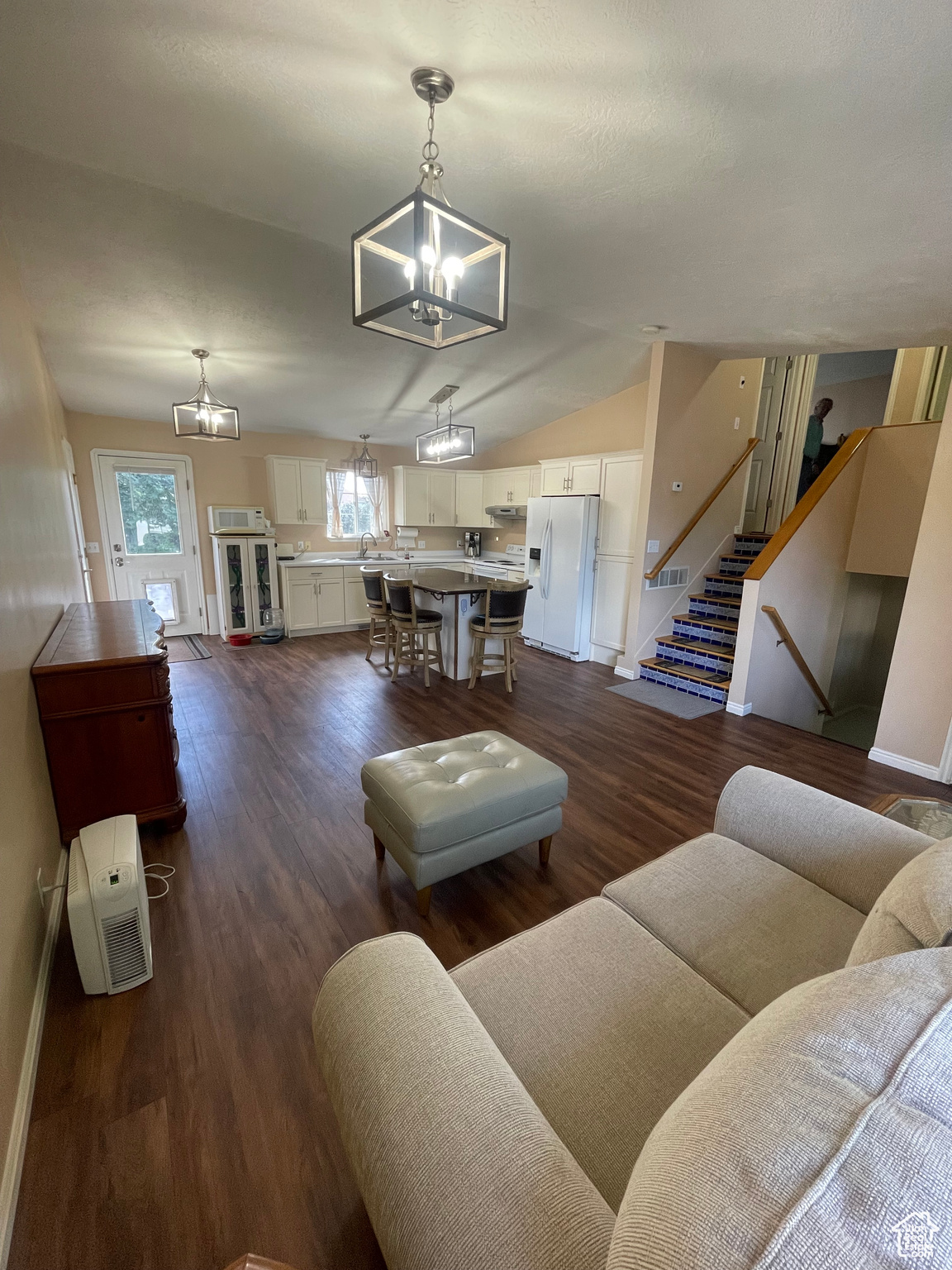 Living room adjacent to Kitchen w/ Island and door to deck and garage.