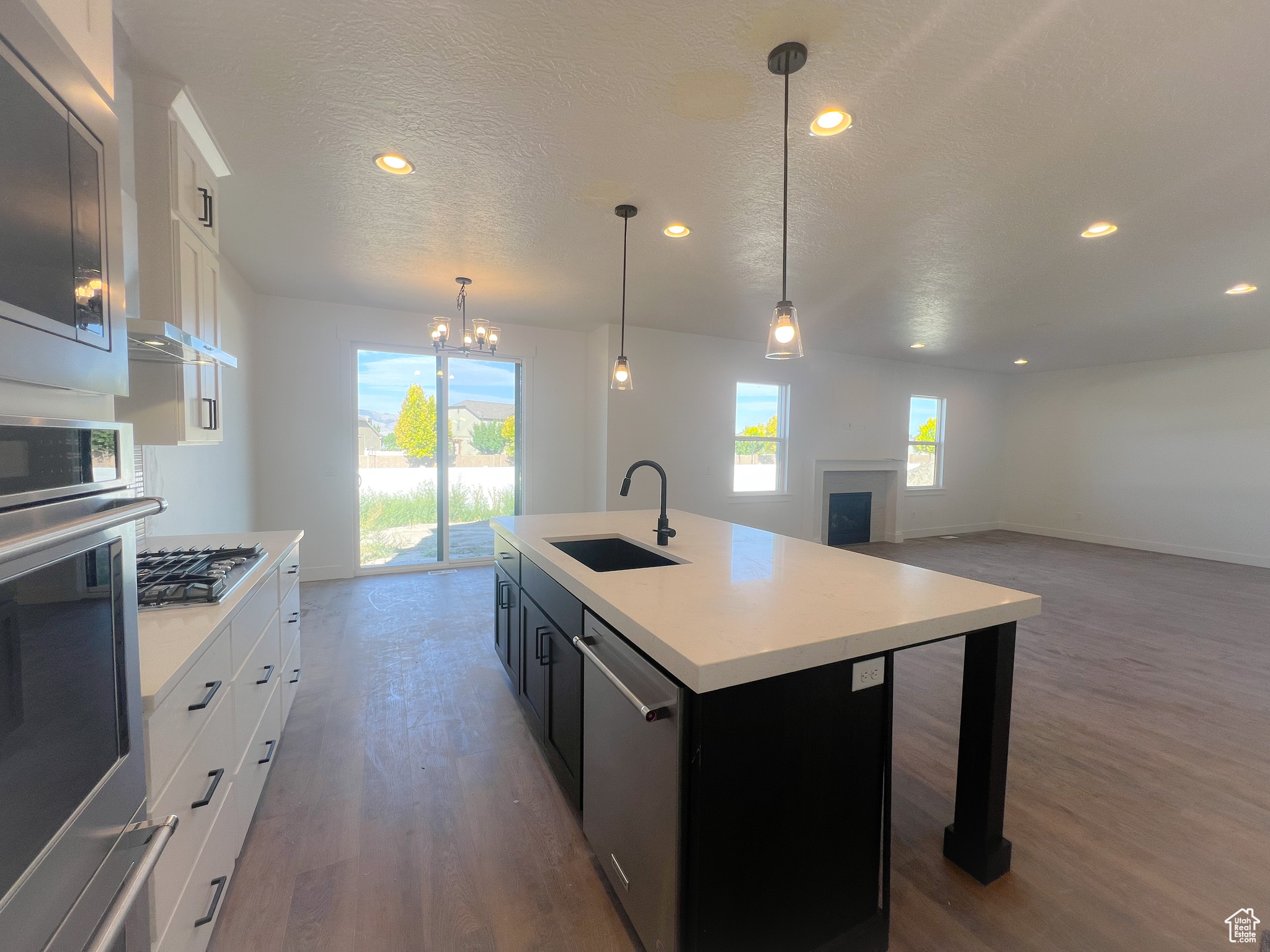 Kitchen featuring sink, stainless steel appliances, a center island with sink, and white cabinets