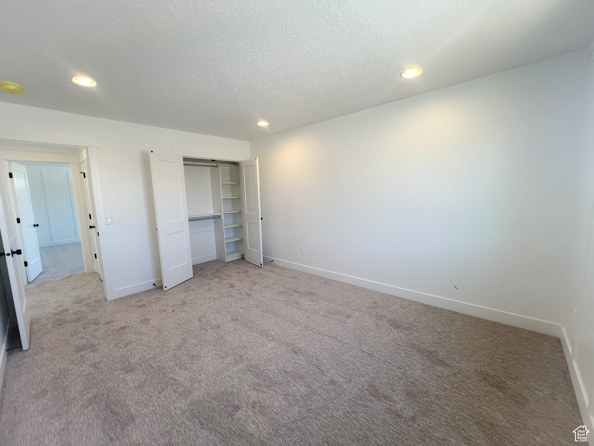 Unfurnished bedroom featuring a closet, light colored carpet, and a textured ceiling