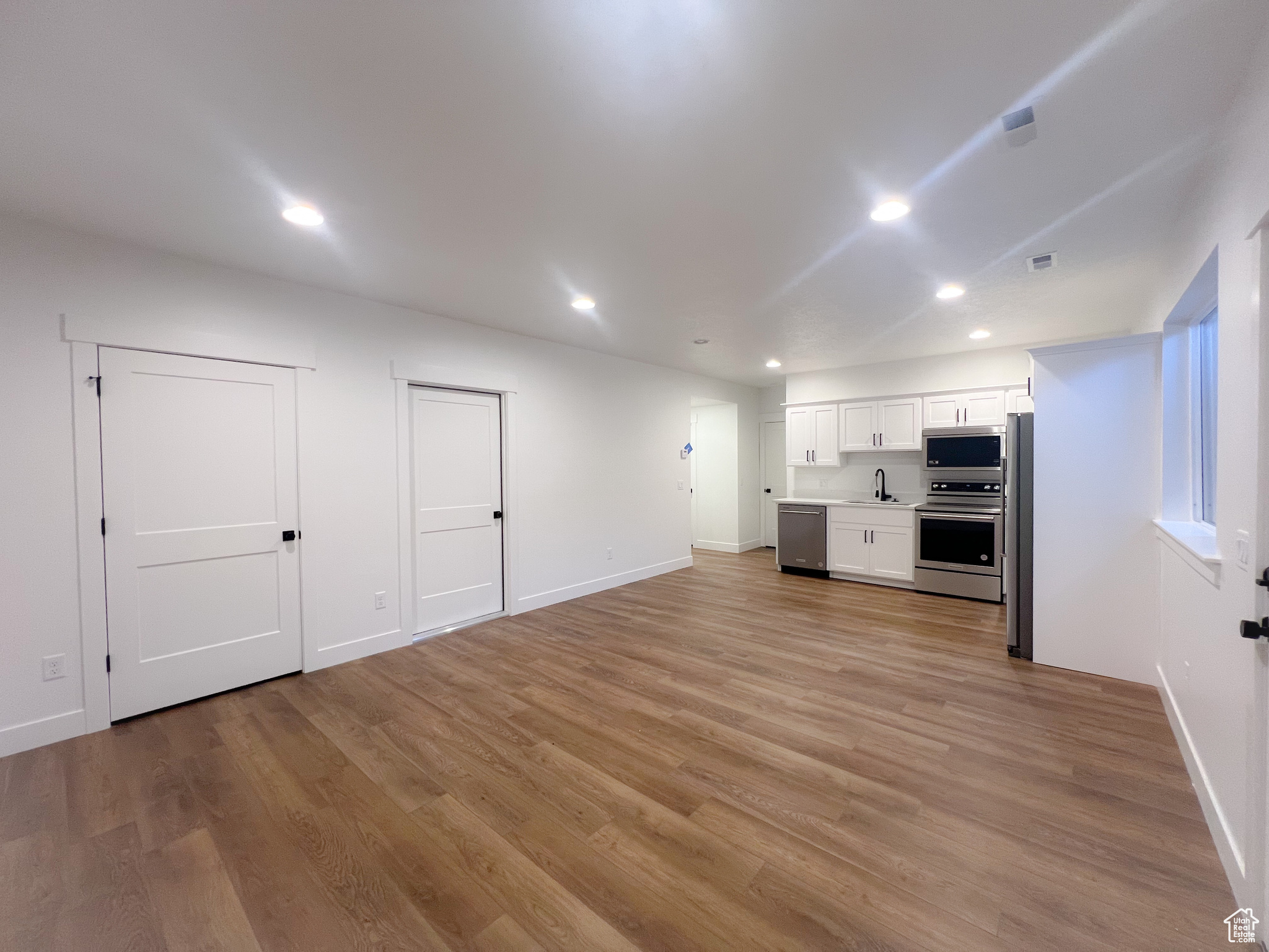 Unfurnished living room featuring sink and light hardwood / wood-style floors