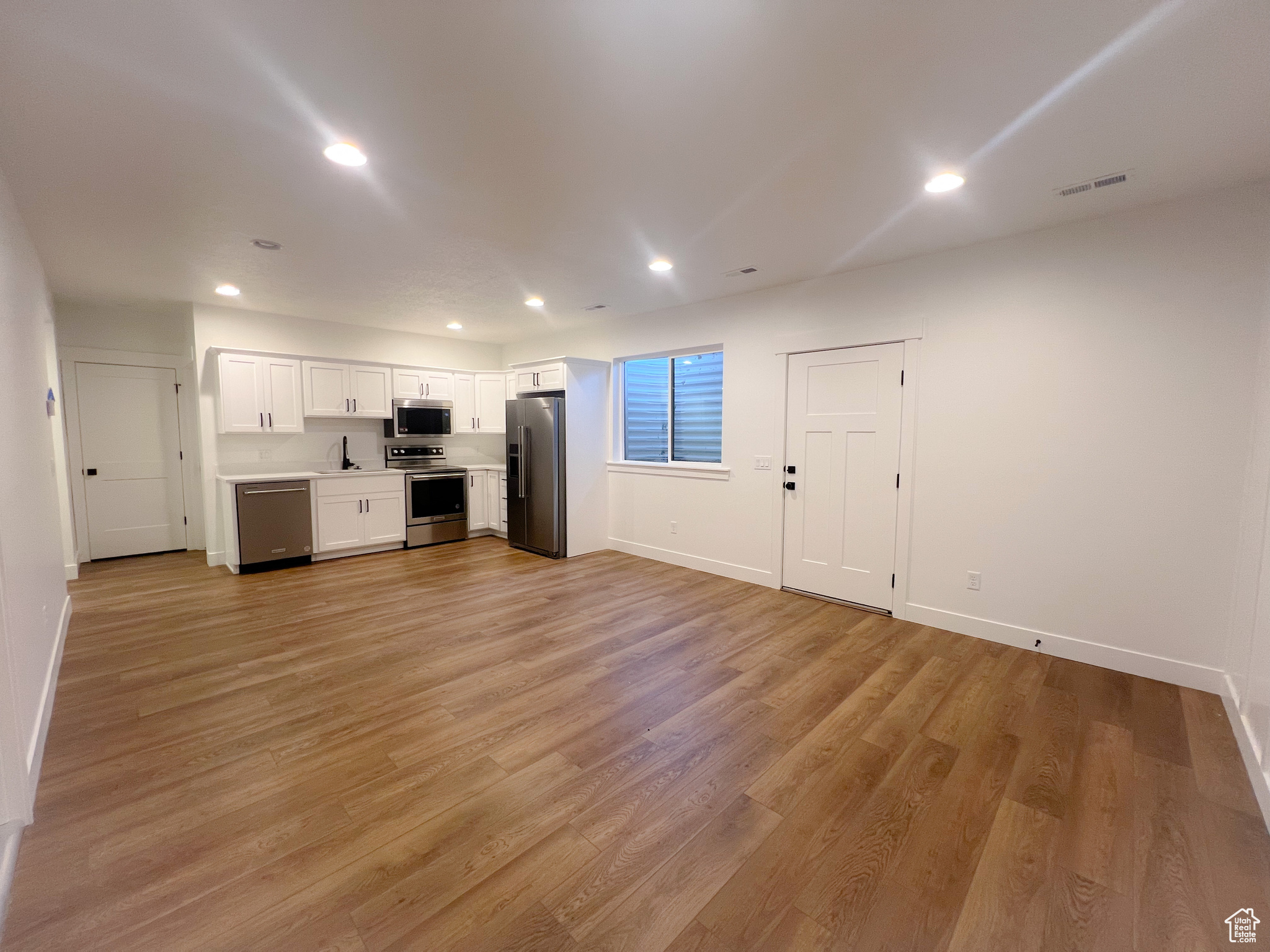 Unfurnished living room with sink and light hardwood / wood-style flooring