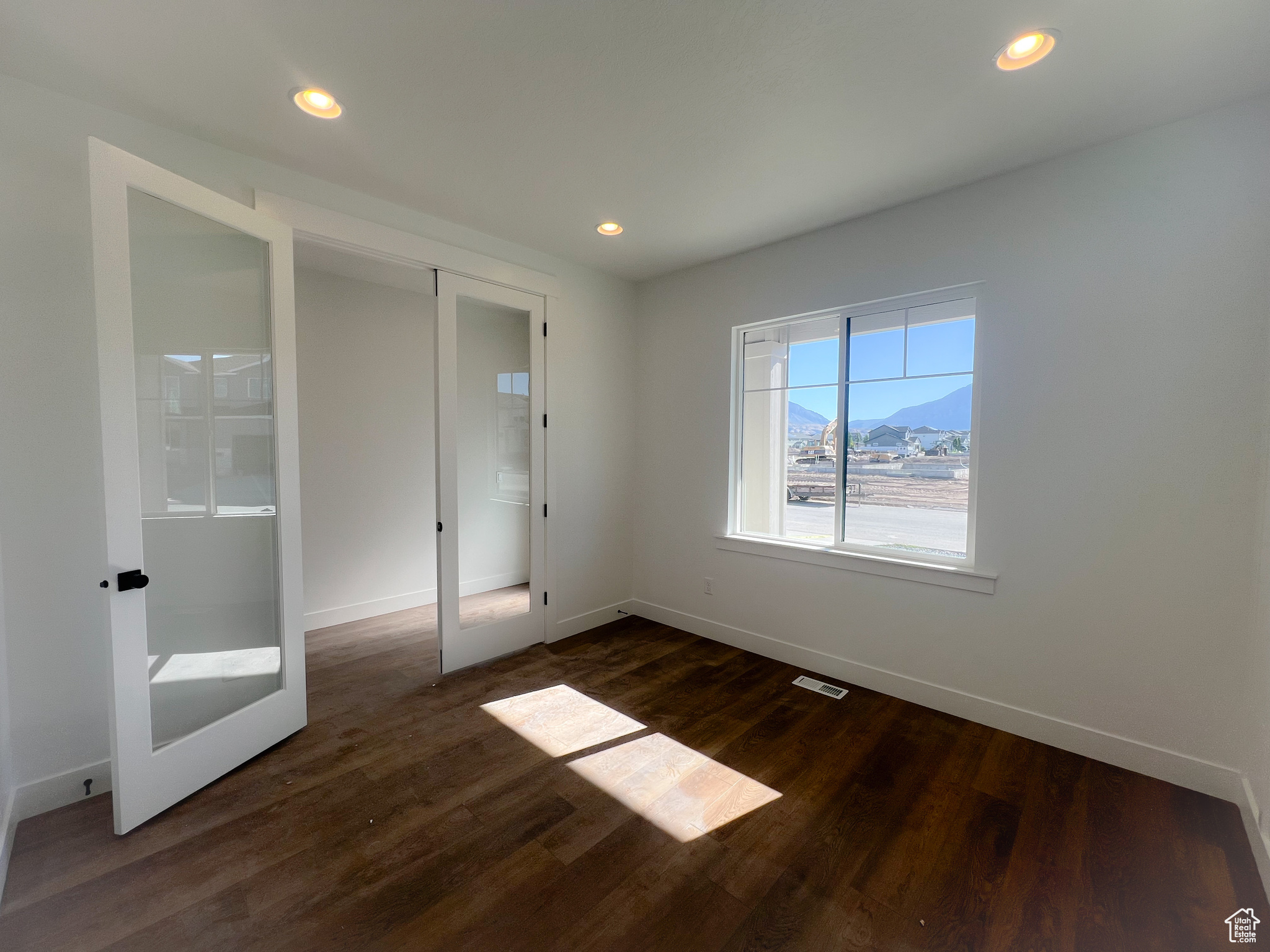 Unfurnished bedroom with dark wood-type flooring and french doors