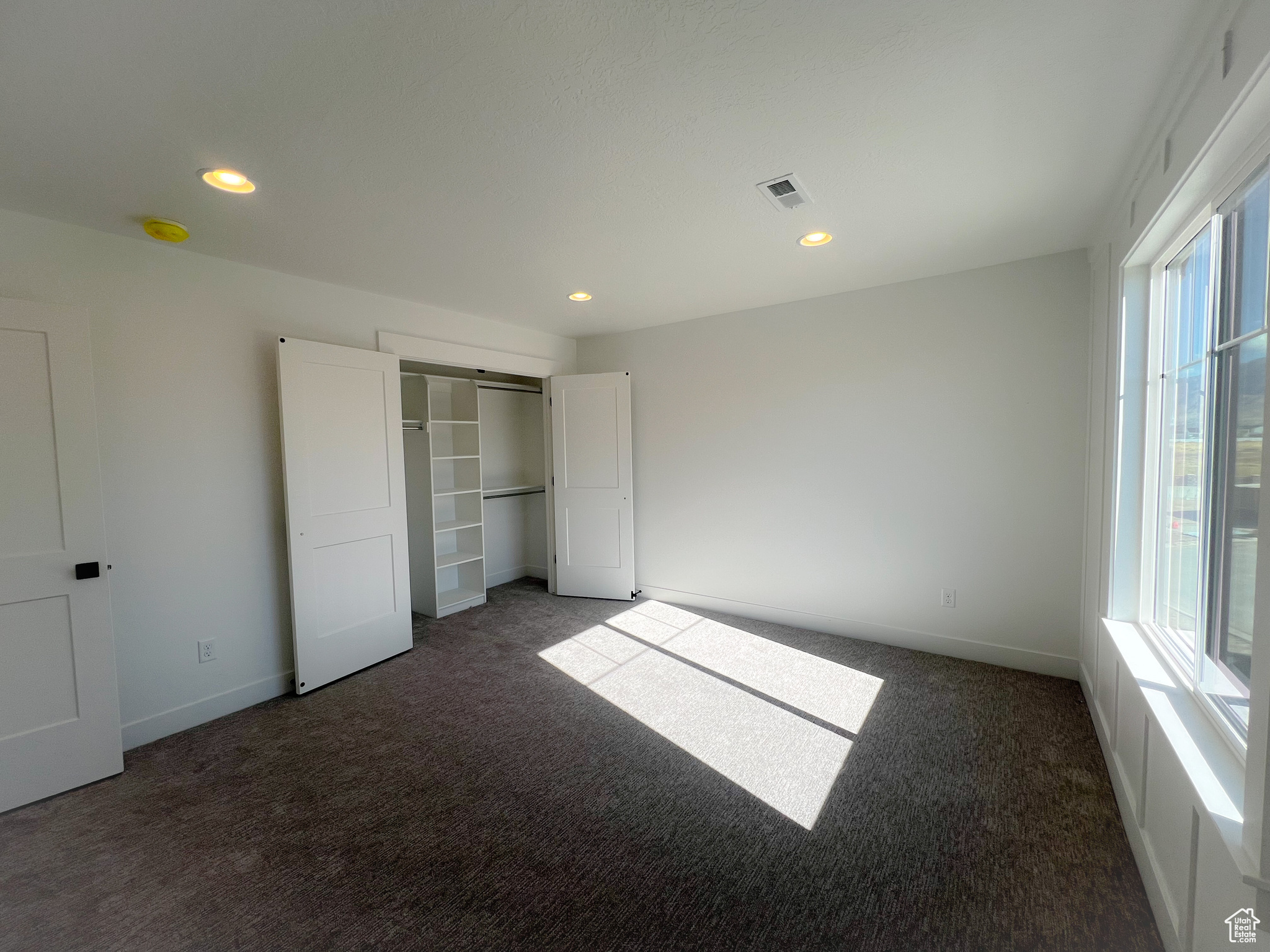 Unfurnished bedroom featuring a closet and dark carpet