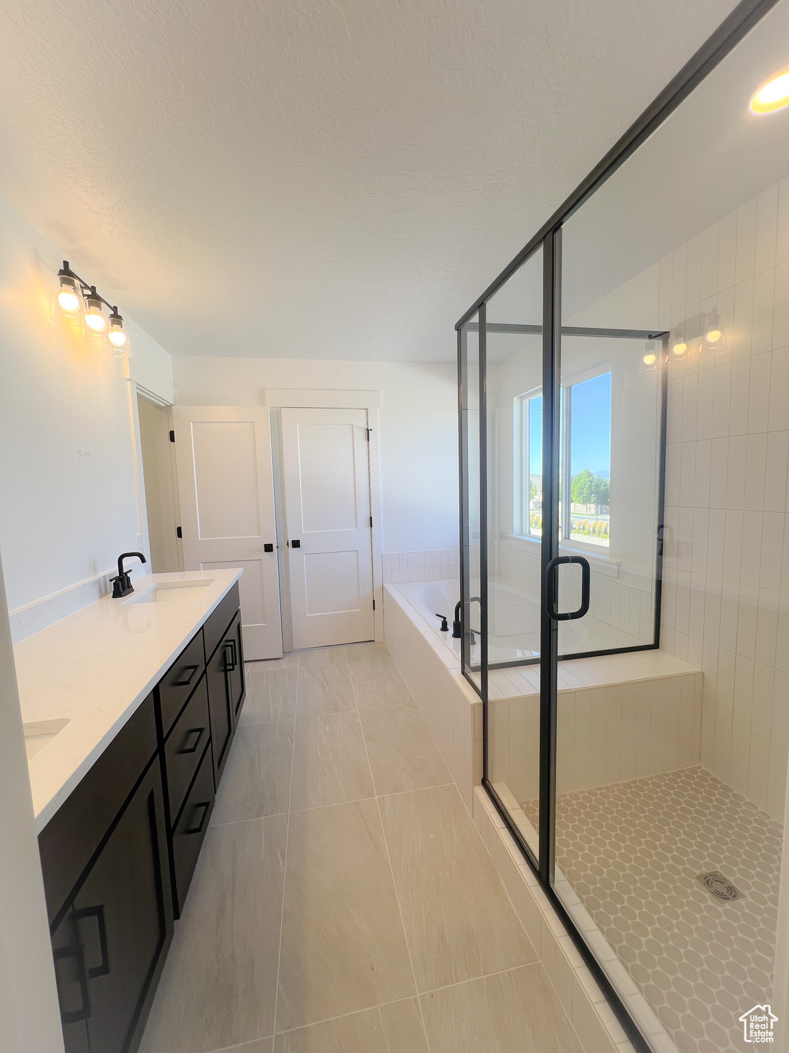 Bathroom with tile patterned flooring, independent shower and bath, and vanity