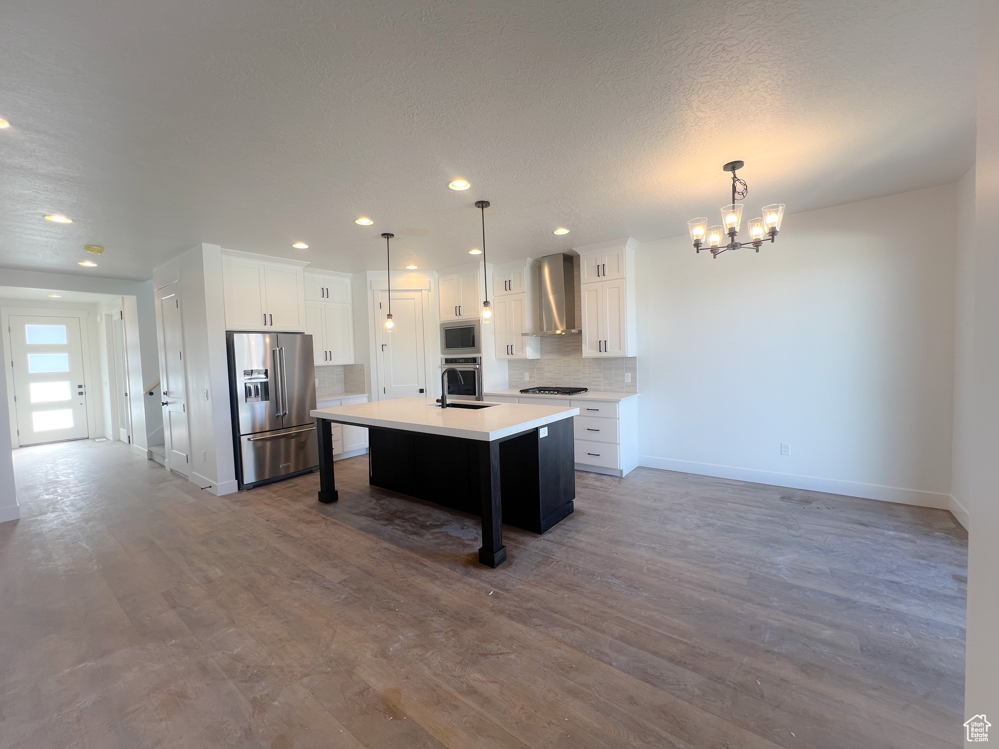 Kitchen featuring a center island, dark hardwood / wood-style floors, white cabinetry, stainless steel appliances, and pendant lighting