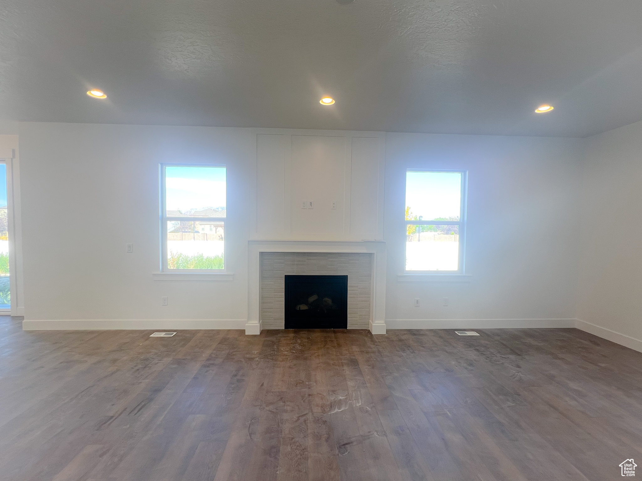 Unfurnished living room featuring a wealth of natural light, a fireplace, and wood-type flooring