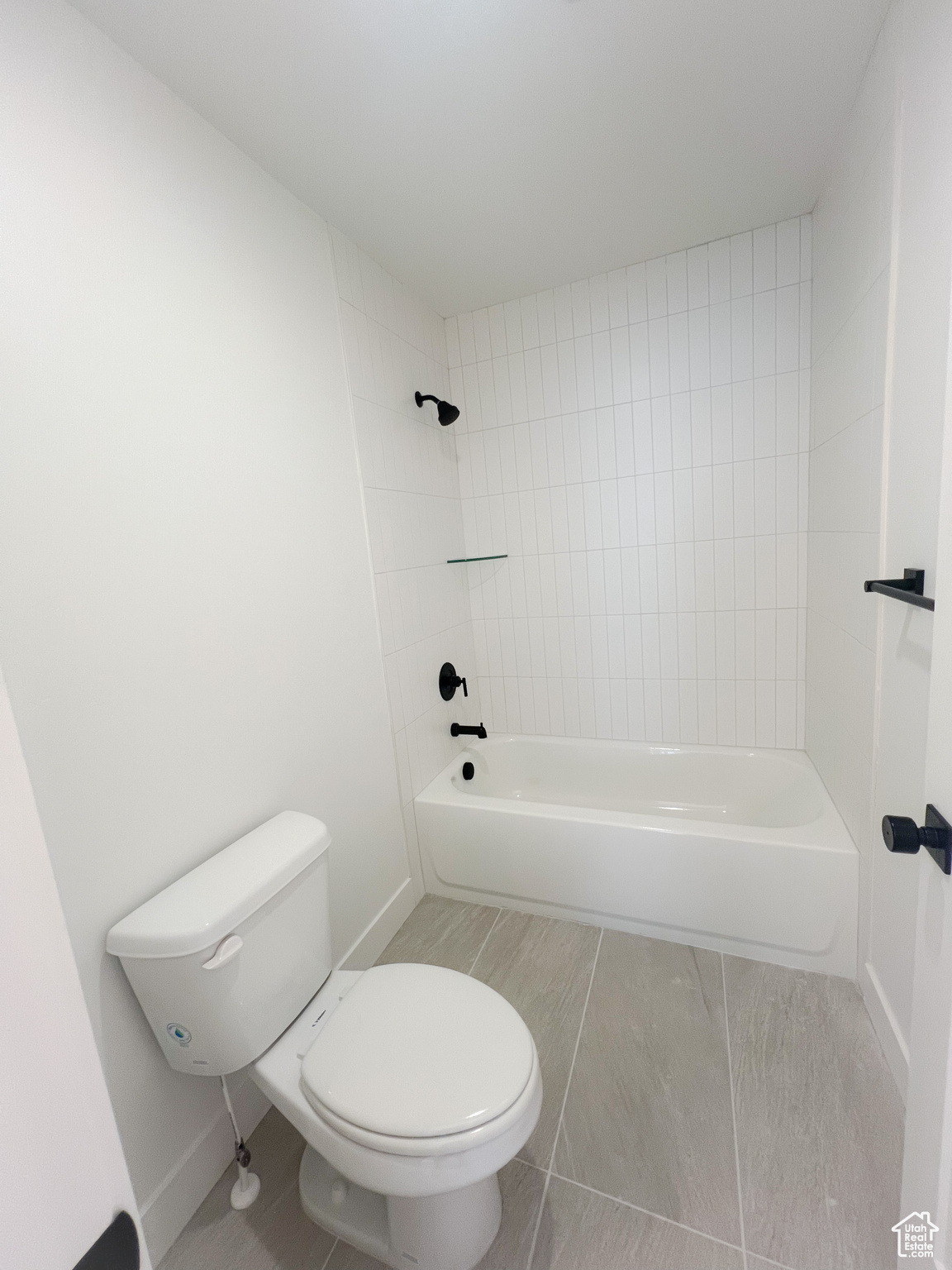 Bathroom with tile patterned flooring, toilet, and tiled shower / bath combo