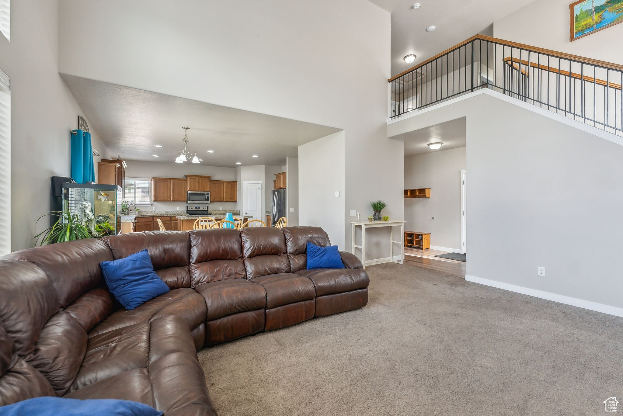 Living room featuring a high ceiling, a chandelier, and light colored carpet