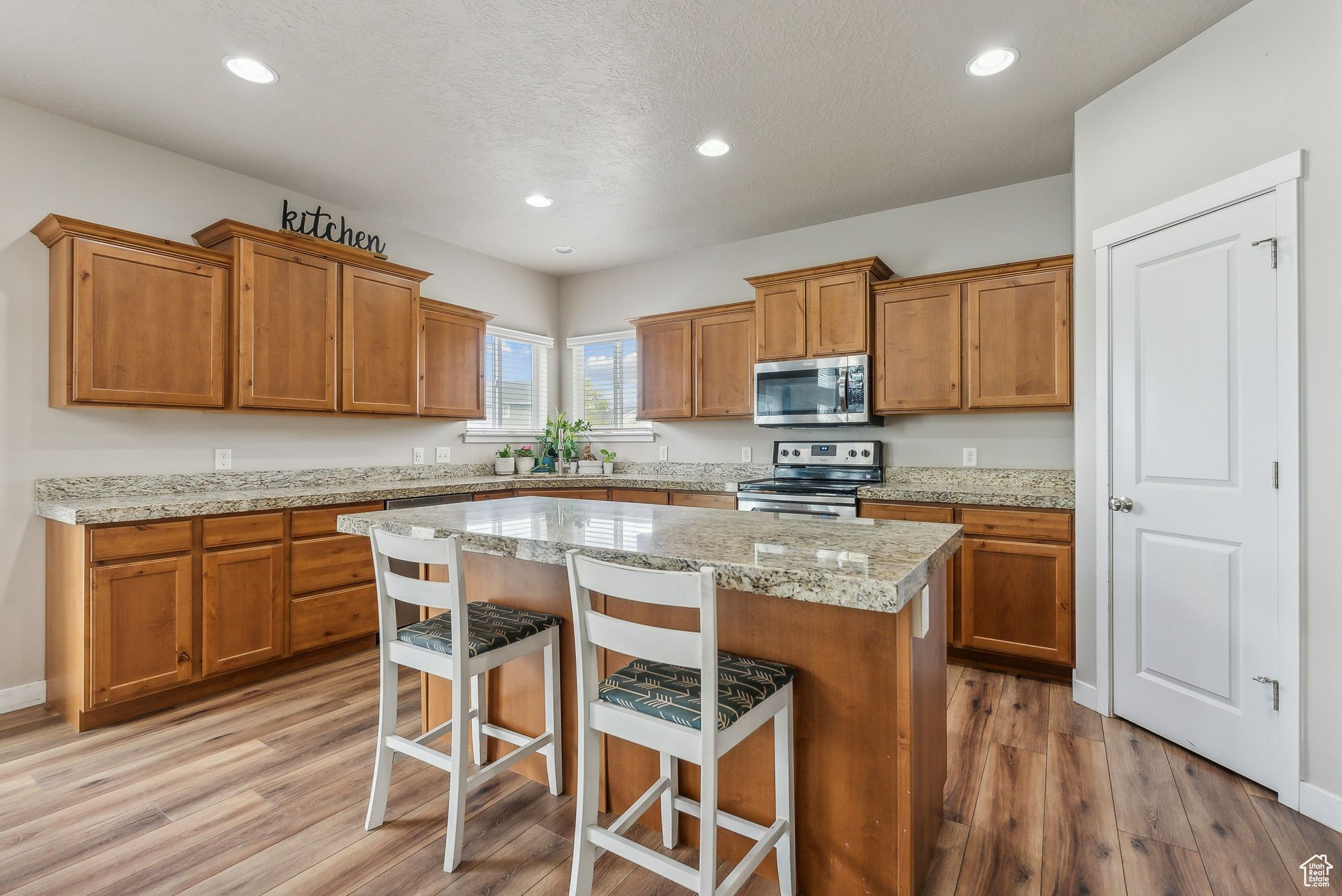 Kitchen with appliances with stainless steel finishes, a breakfast bar area, light hardwood / wood-style flooring, and a center island