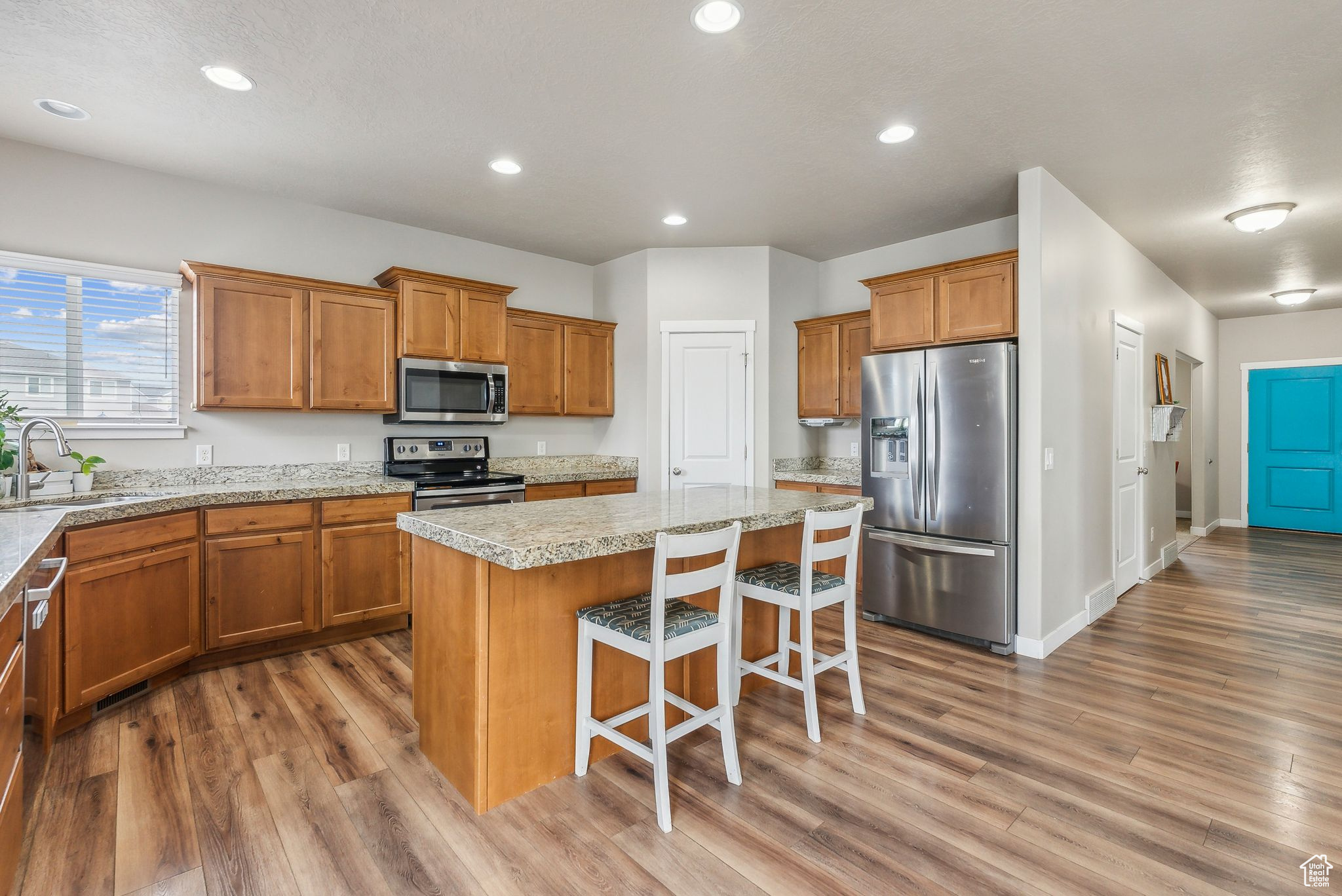 Kitchen with stainless steel appliances, hardwood / wood-style floors, sink, a kitchen breakfast bar, and a center island