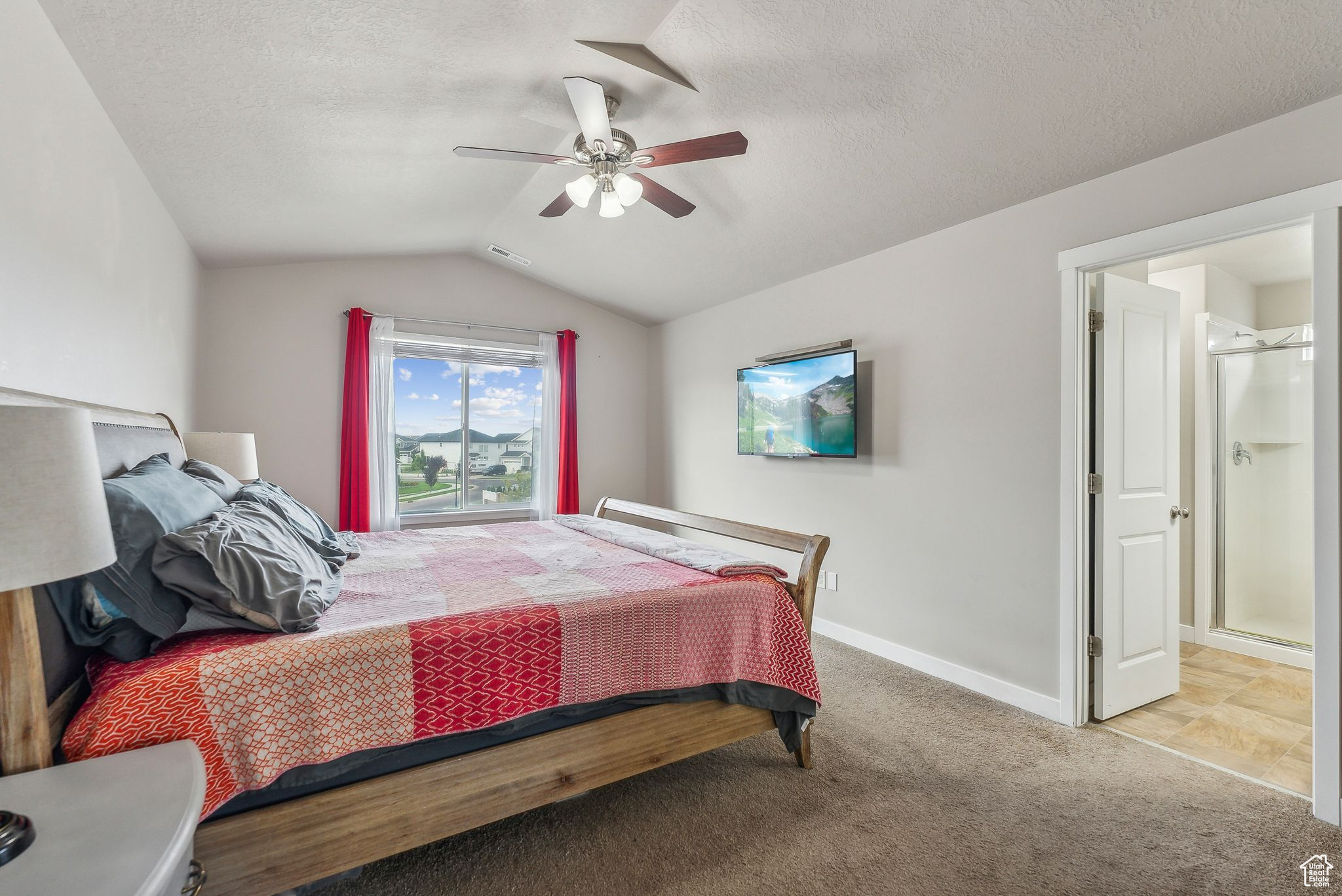 Bedroom with ceiling fan, vaulted ceiling, a textured ceiling, and light tile patterned floors