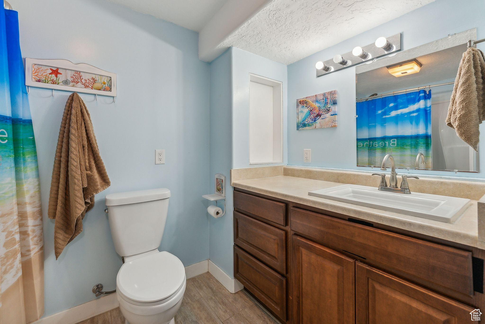 Bathroom with a textured ceiling, toilet, vanity, and wood-type flooring