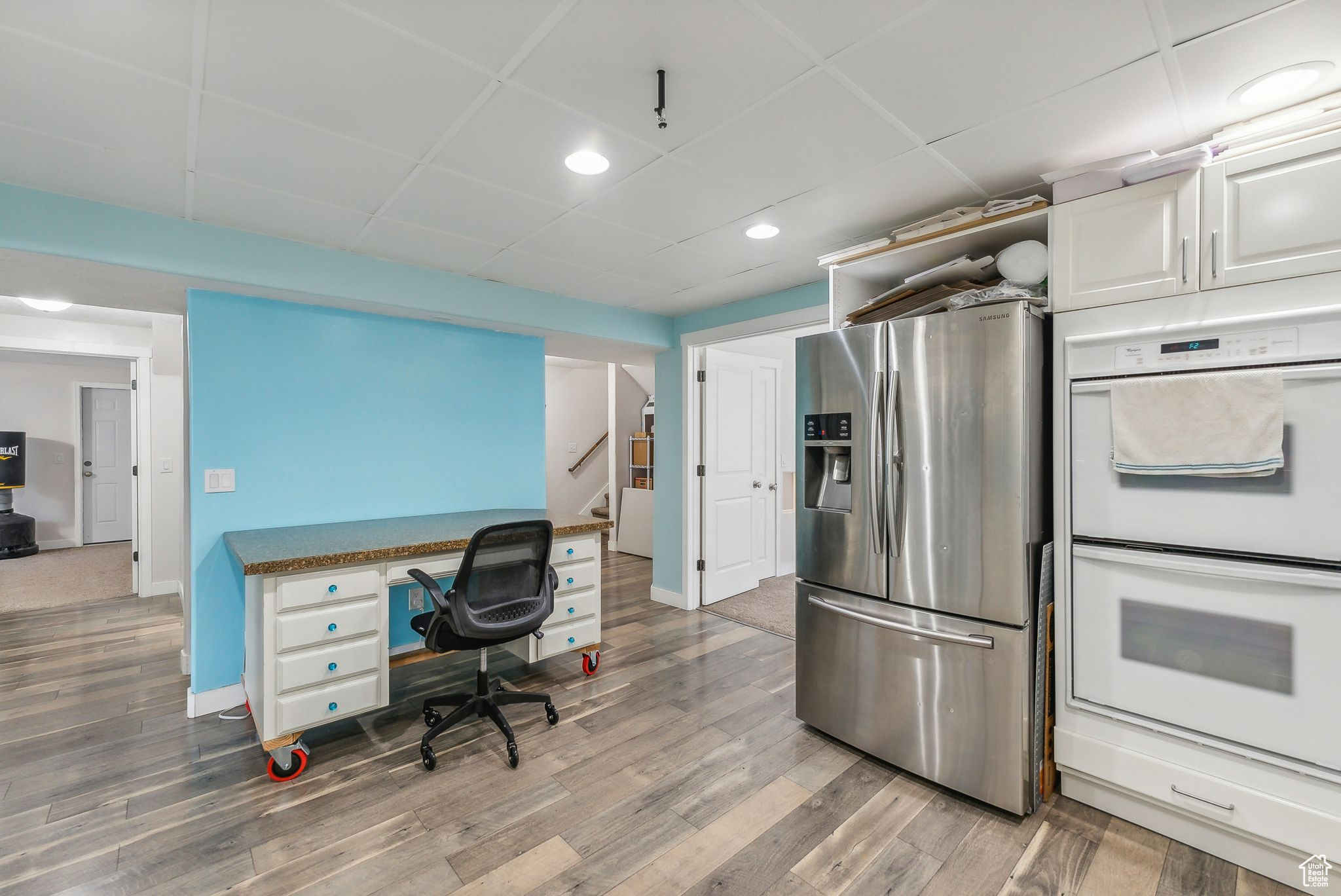 Kitchen with light wood-type flooring, white double oven, and stainless steel fridge