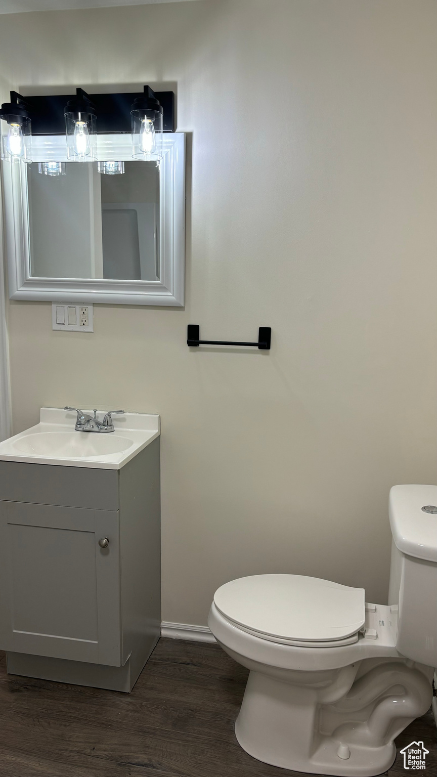 Bathroom with toilet, vanity, and hardwood / wood-style flooring